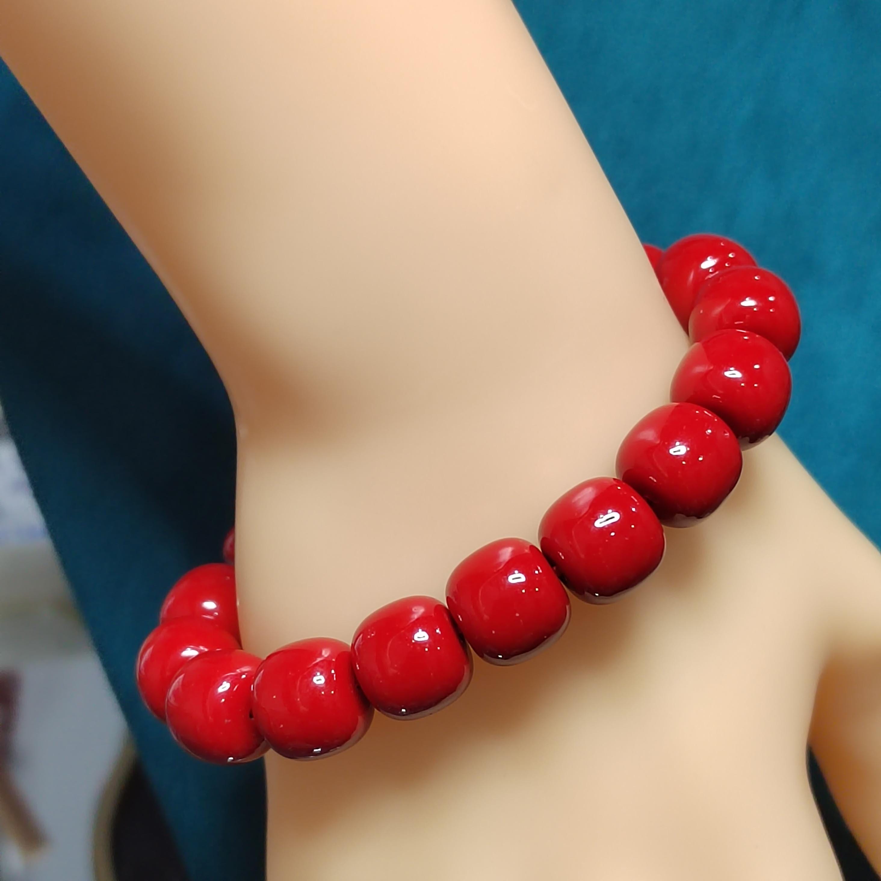 Red beaded bracelet on a person's wrist with a blue background