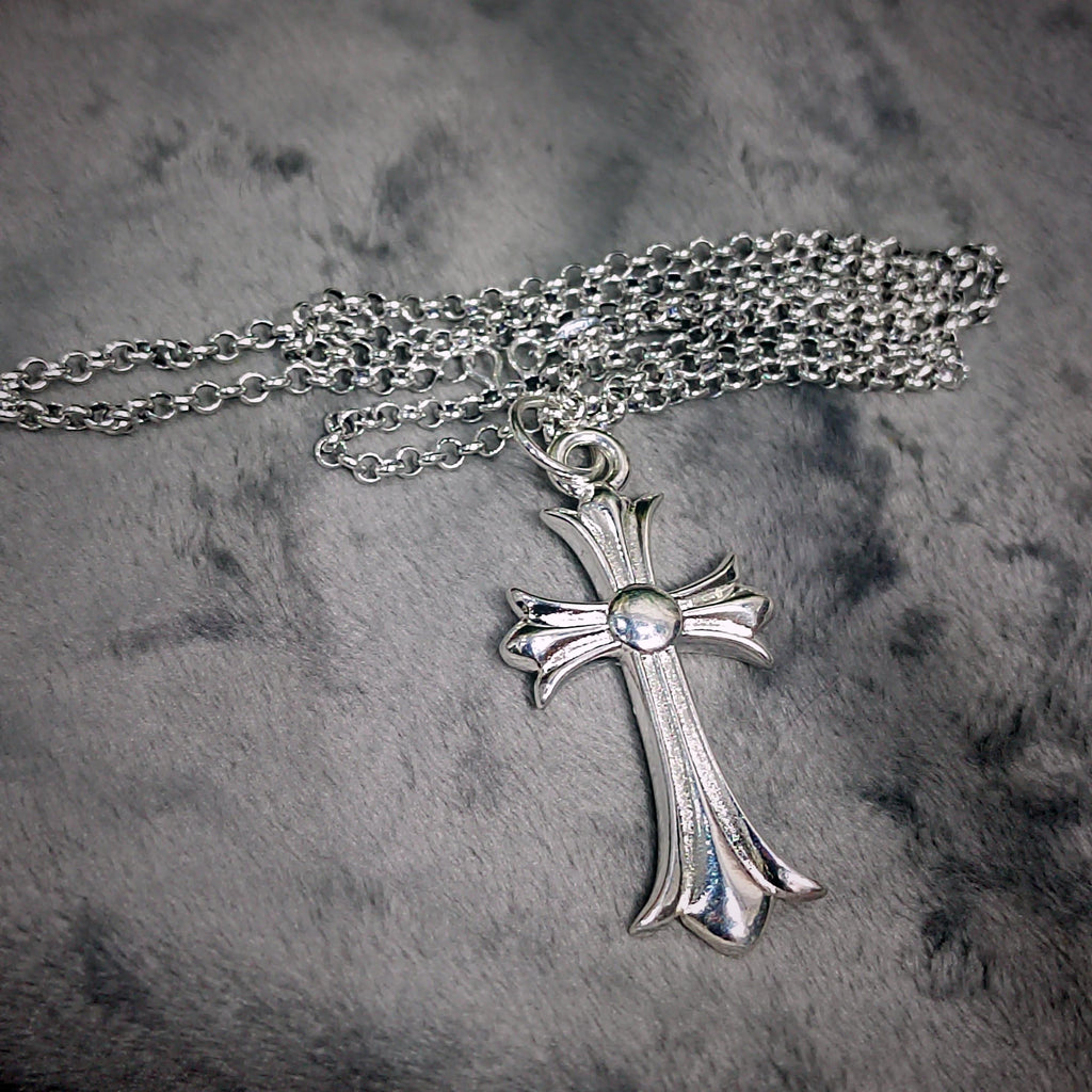 Silver cross necklace on a textured gray background
