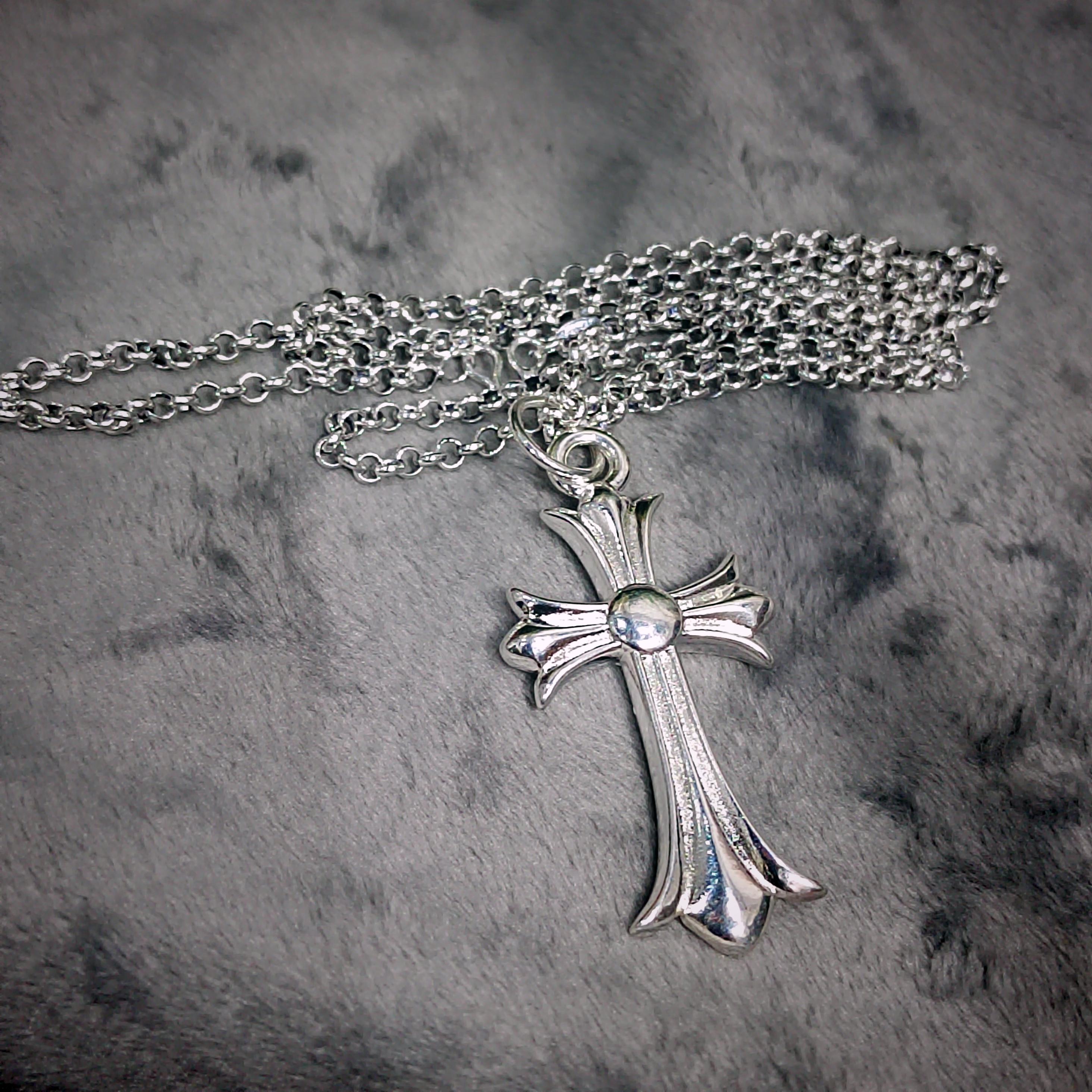 Silver cross necklace on a textured gray background