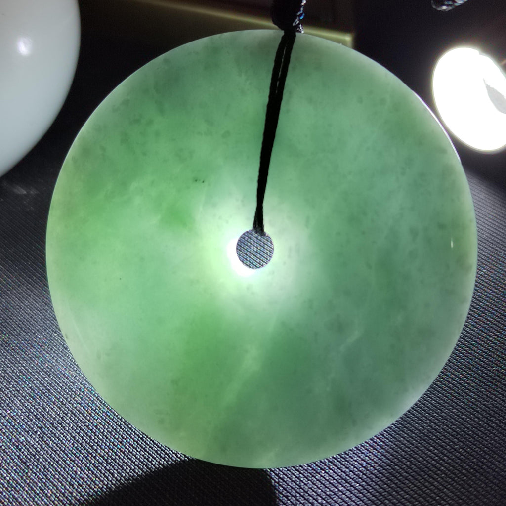 Green jade pendant on a dark textured surface