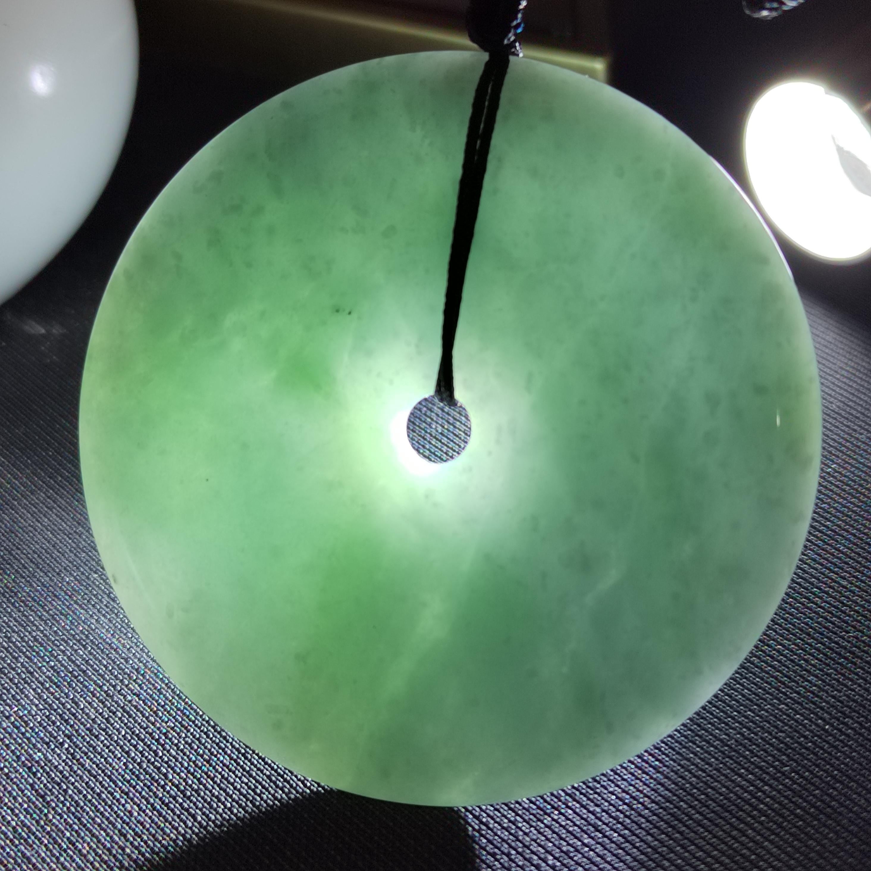 Green jade pendant on a dark textured surface