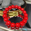 Red beaded bracelet on a reflective surface with a blurred background