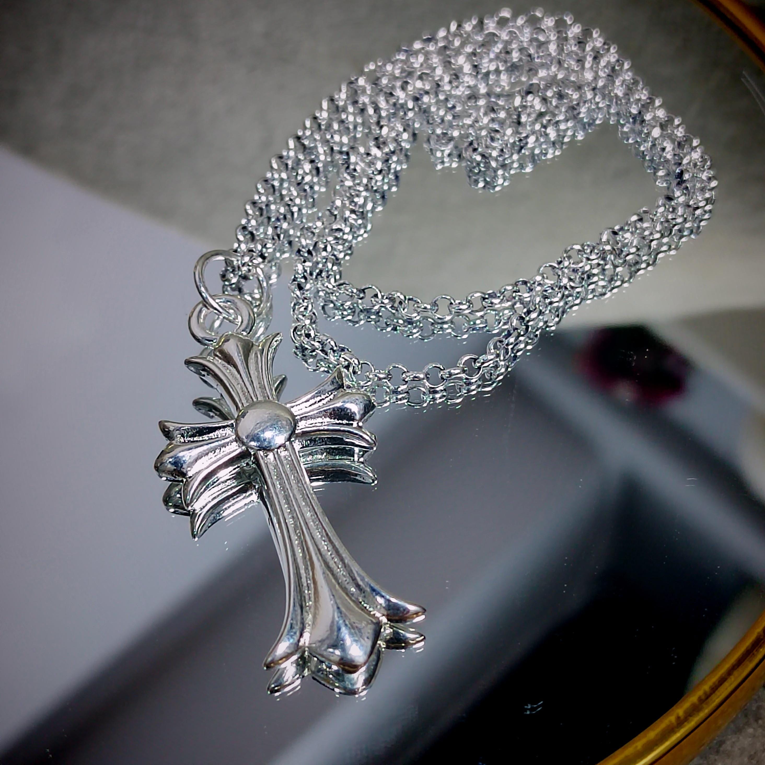 Silver cross necklace on a reflective surface