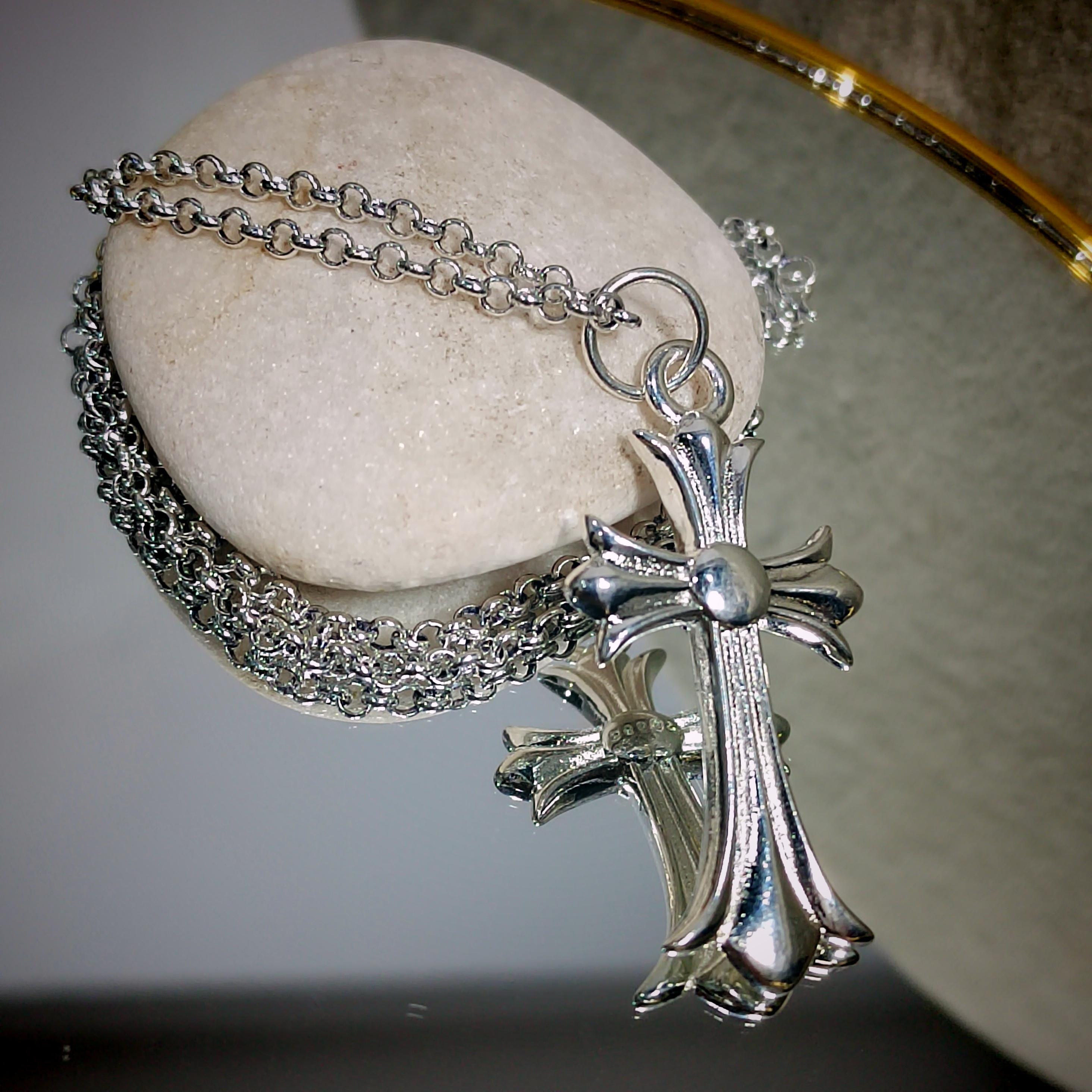 Silver cross necklace on a stone surface