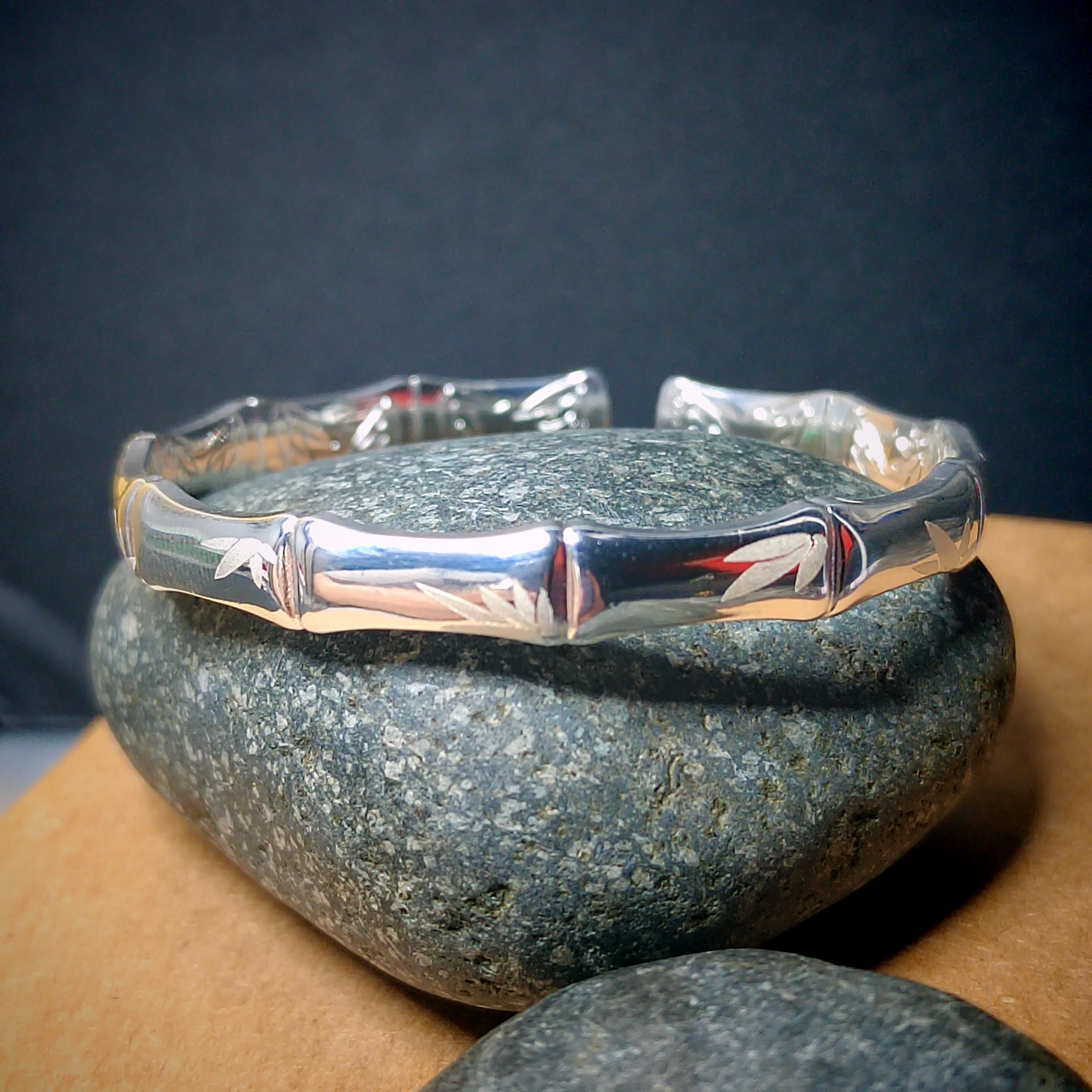 Silver bracelet with intricate designs on a dark stone surface