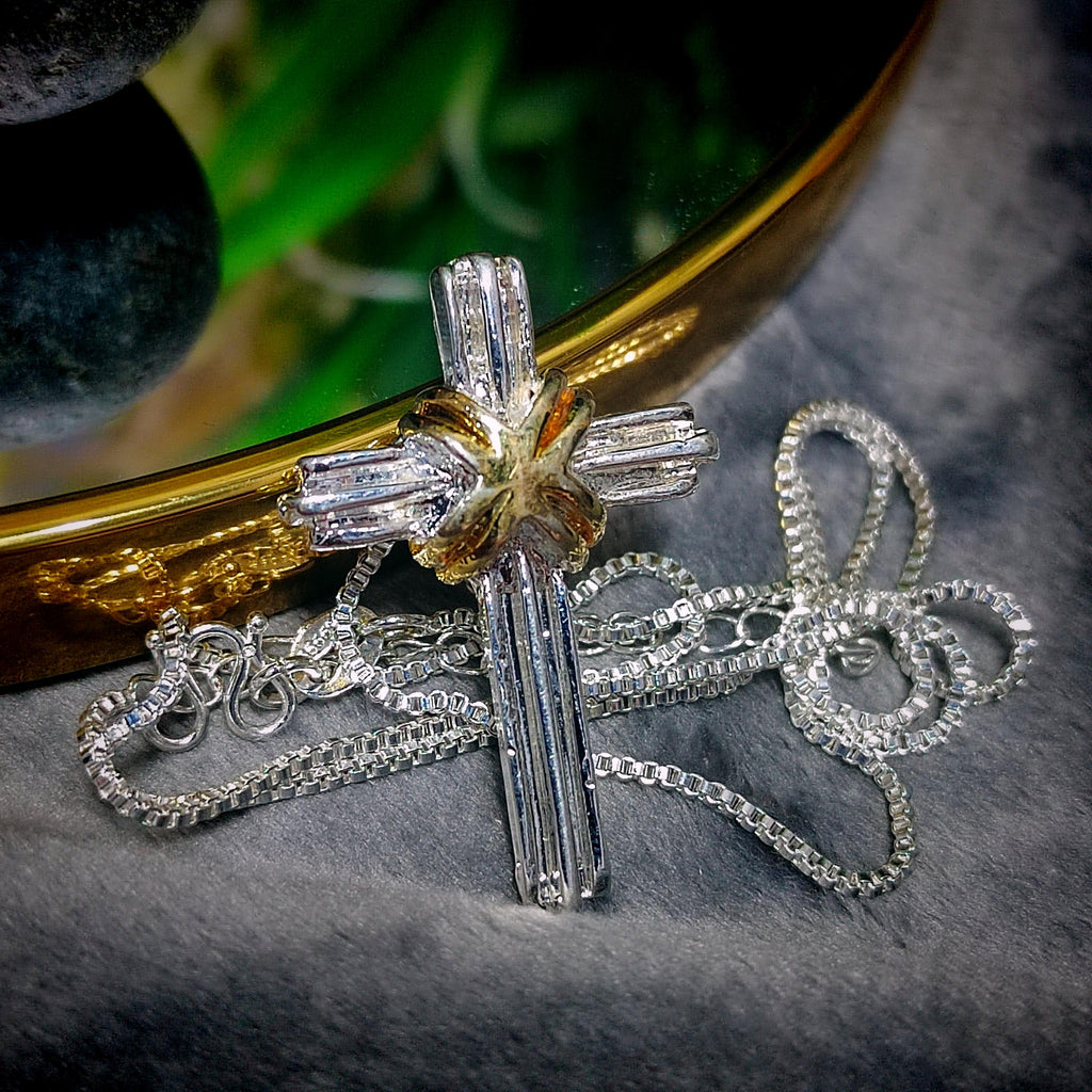 Silver cross necklace with diamond accents on a textured surface