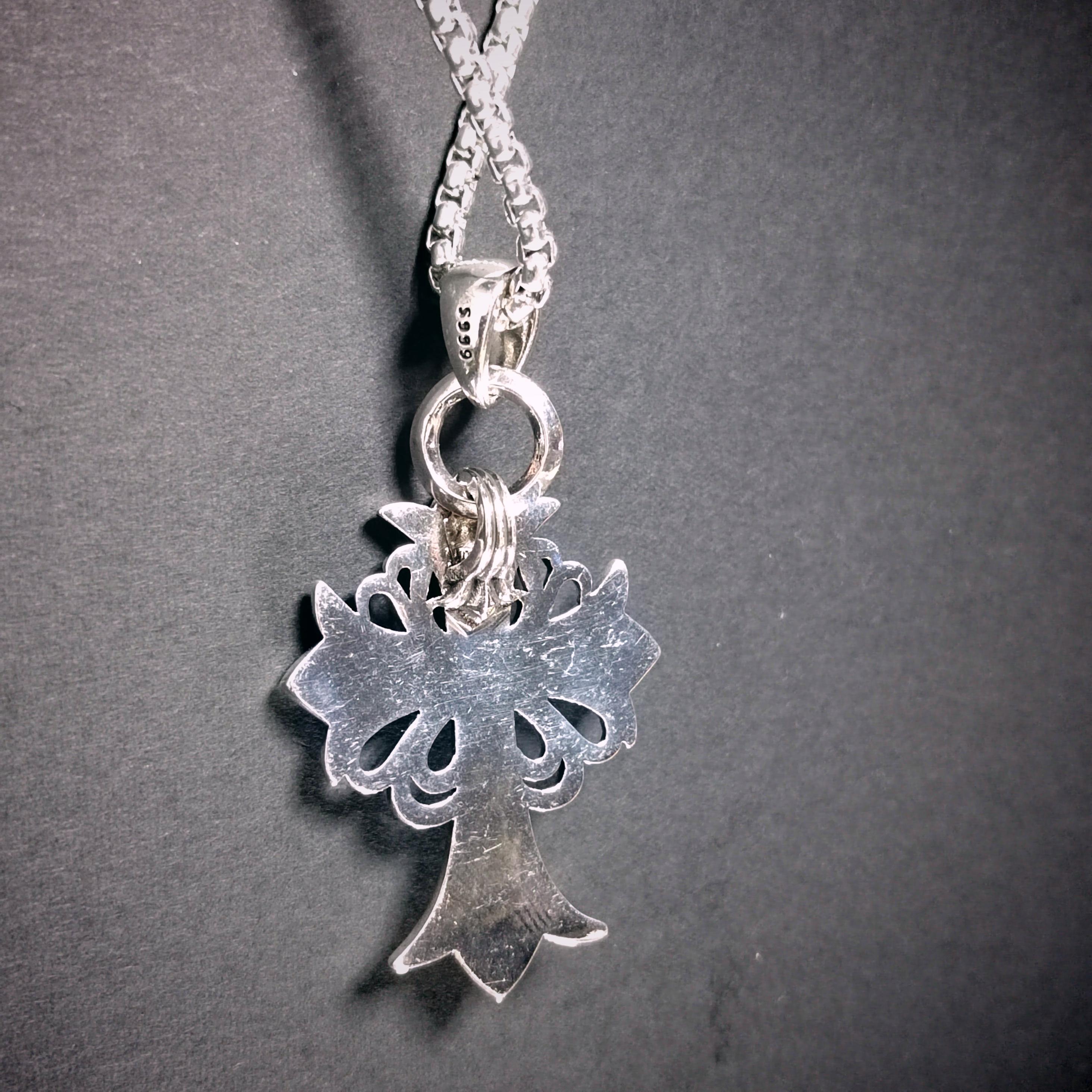 Silver necklace with a tree-shaped pendant on a dark gray background