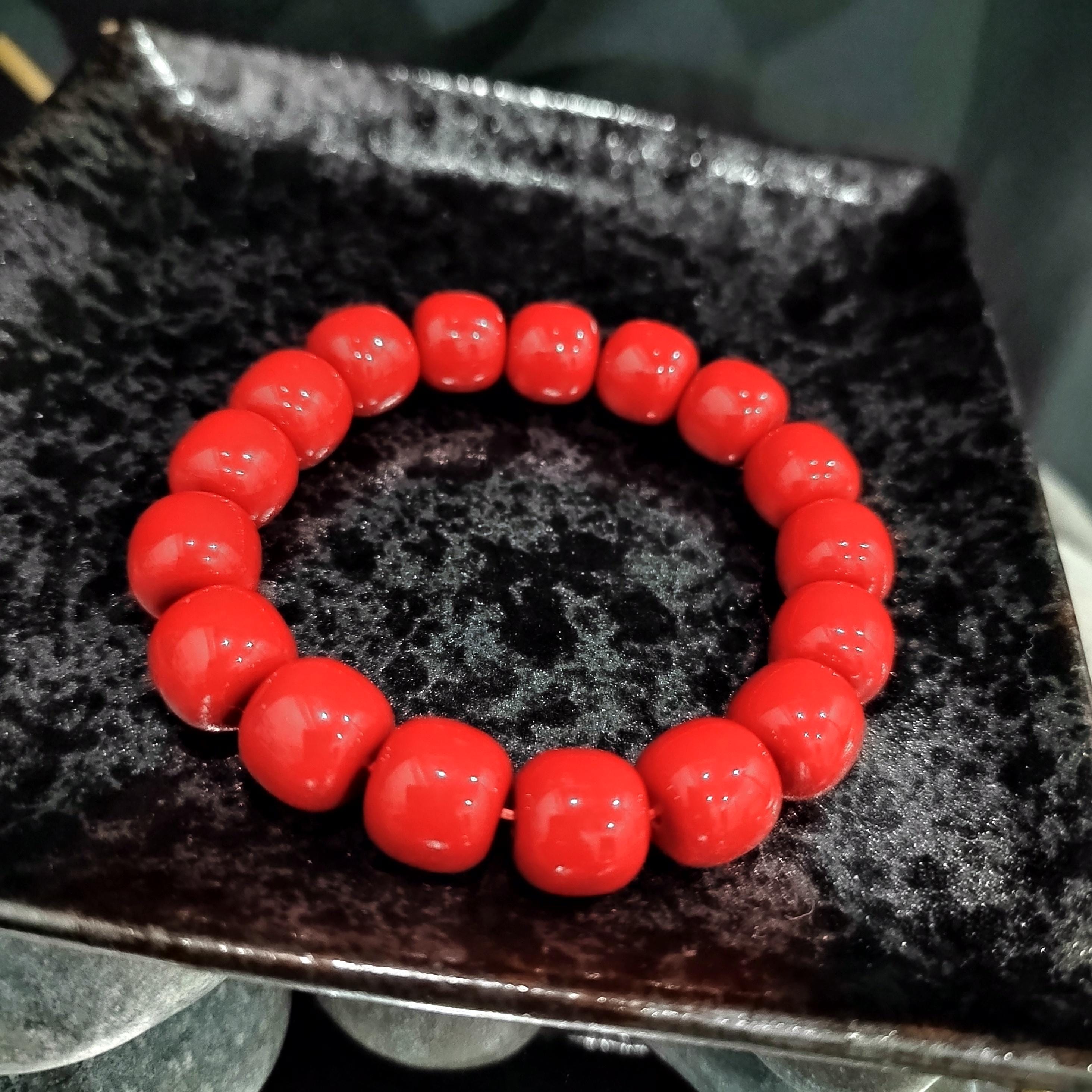 Red beaded bracelet on a textured black surface