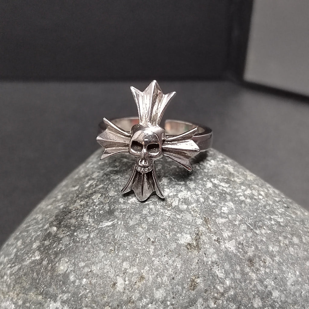 Silver skull and crossbones ring on a textured stone surface