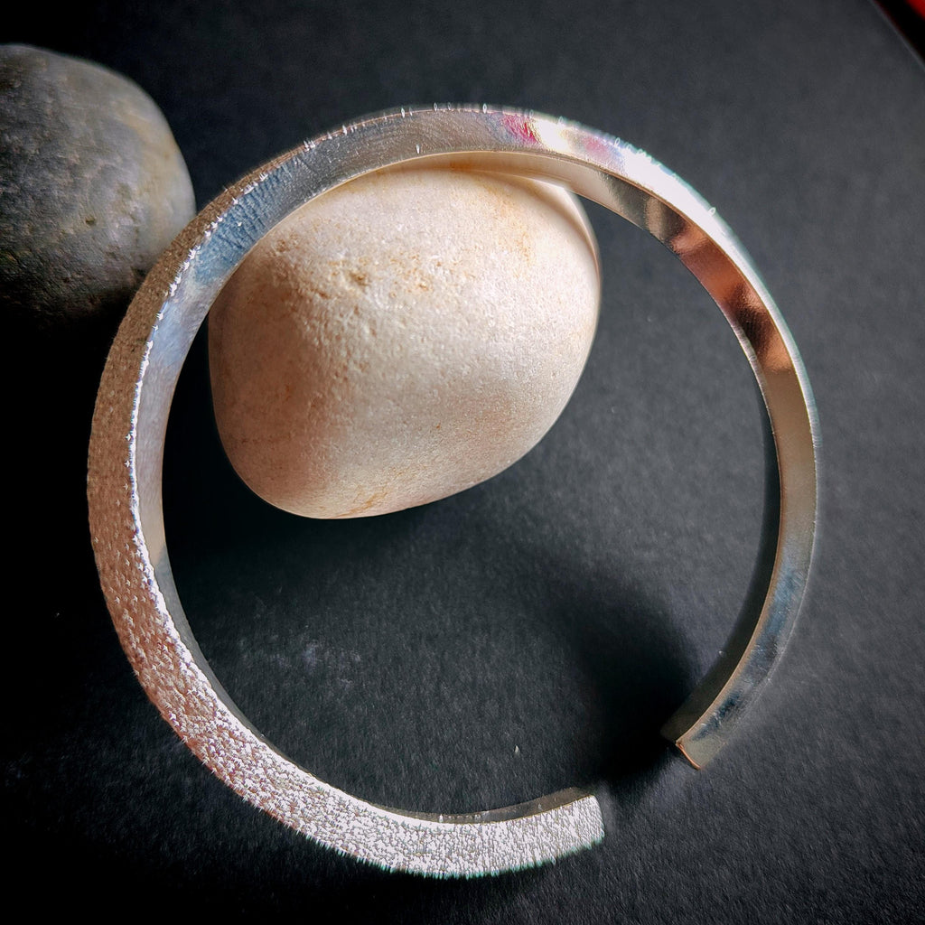 Silver bracelet on a dark surface with stones