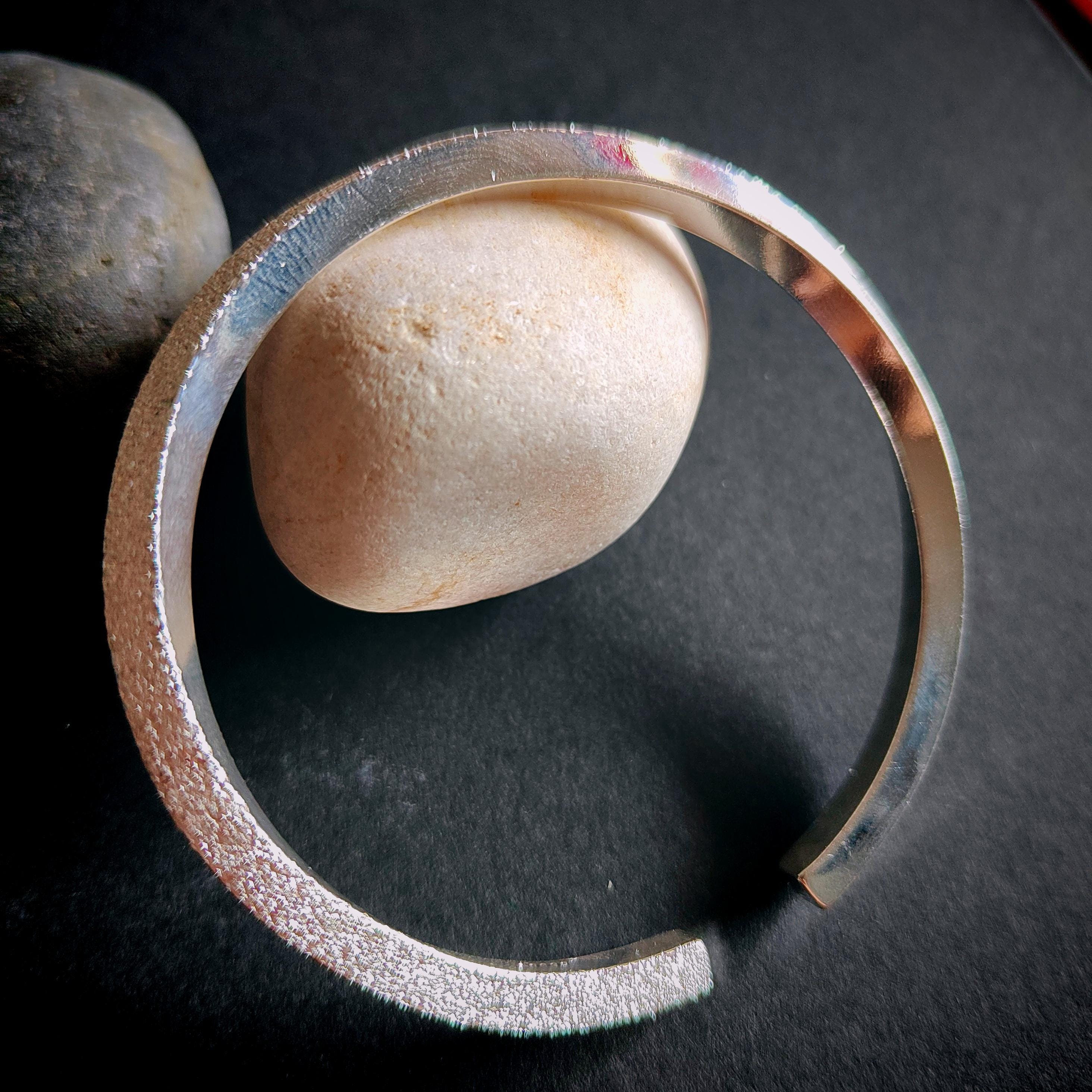 Silver bracelet on a dark surface with stones