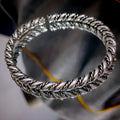Silver braided bracelet on a reflective surface