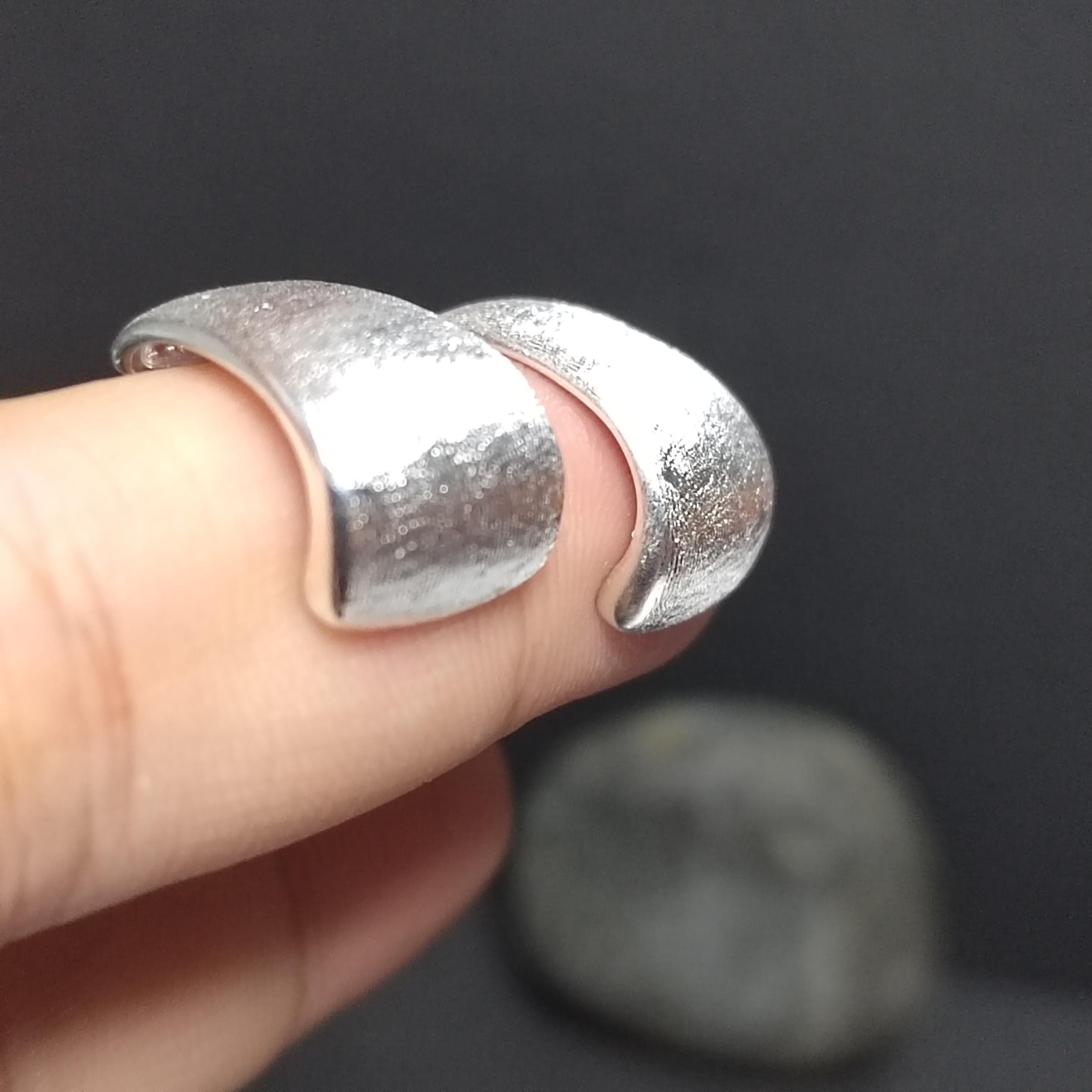Silver ring on a finger against a dark background