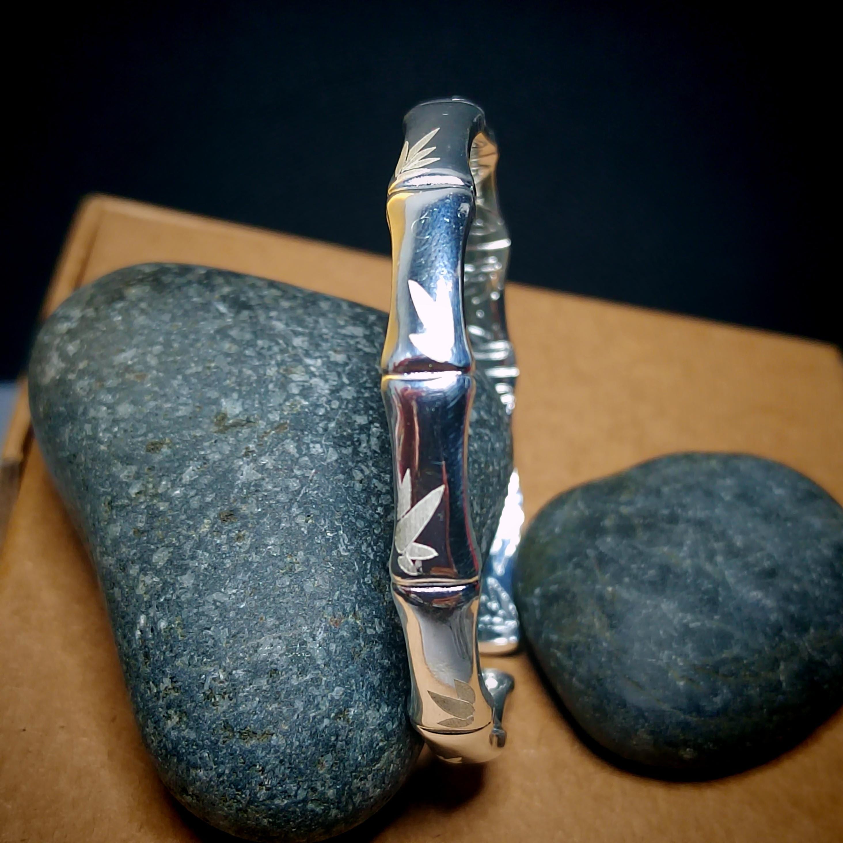 Silver bracelet with leaf design on a dark background