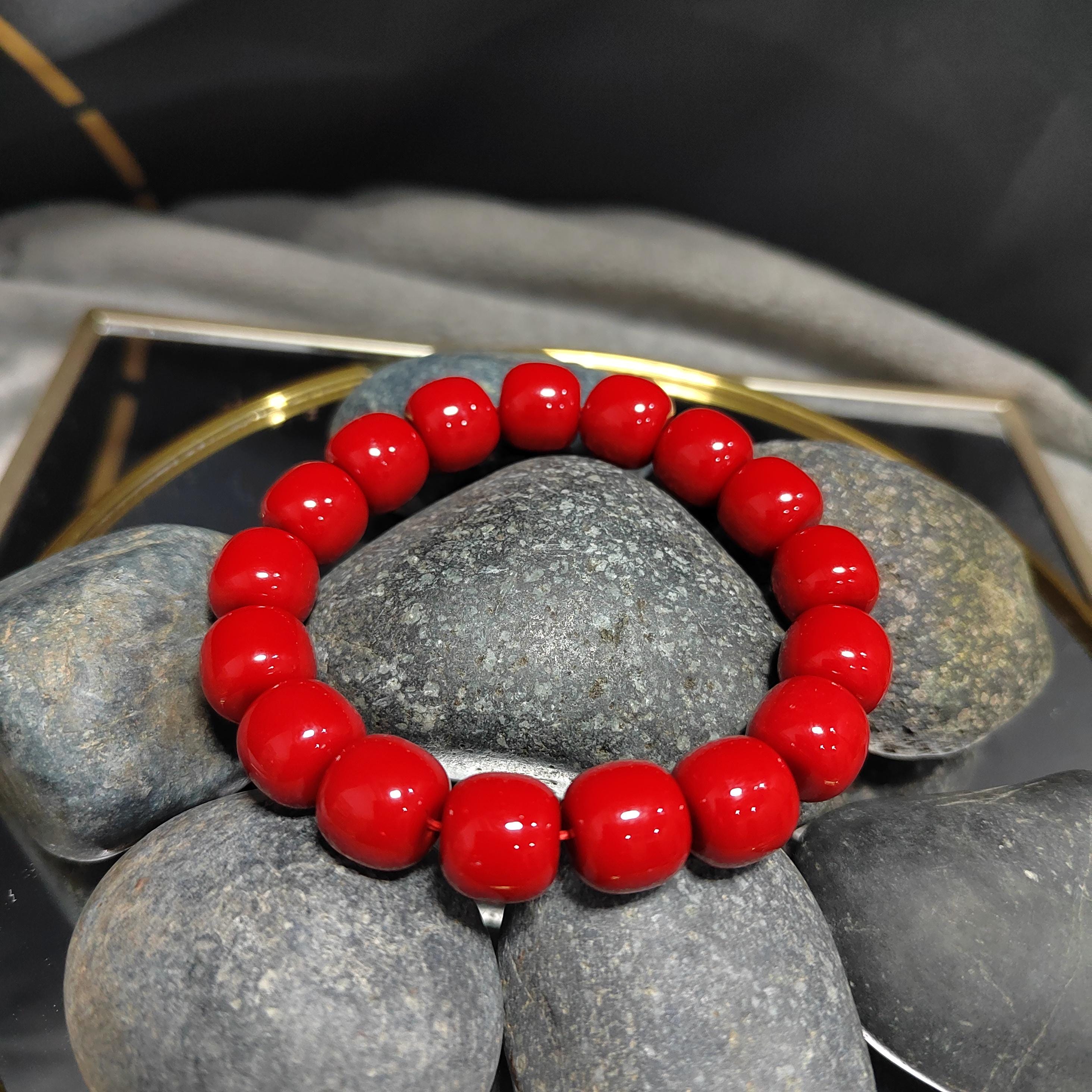Red beaded bracelet on gray stones with a blurred background