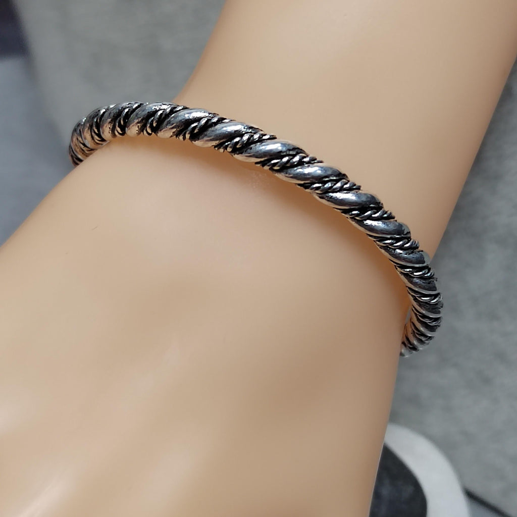Silver braided bracelet on a wrist with a neutral background