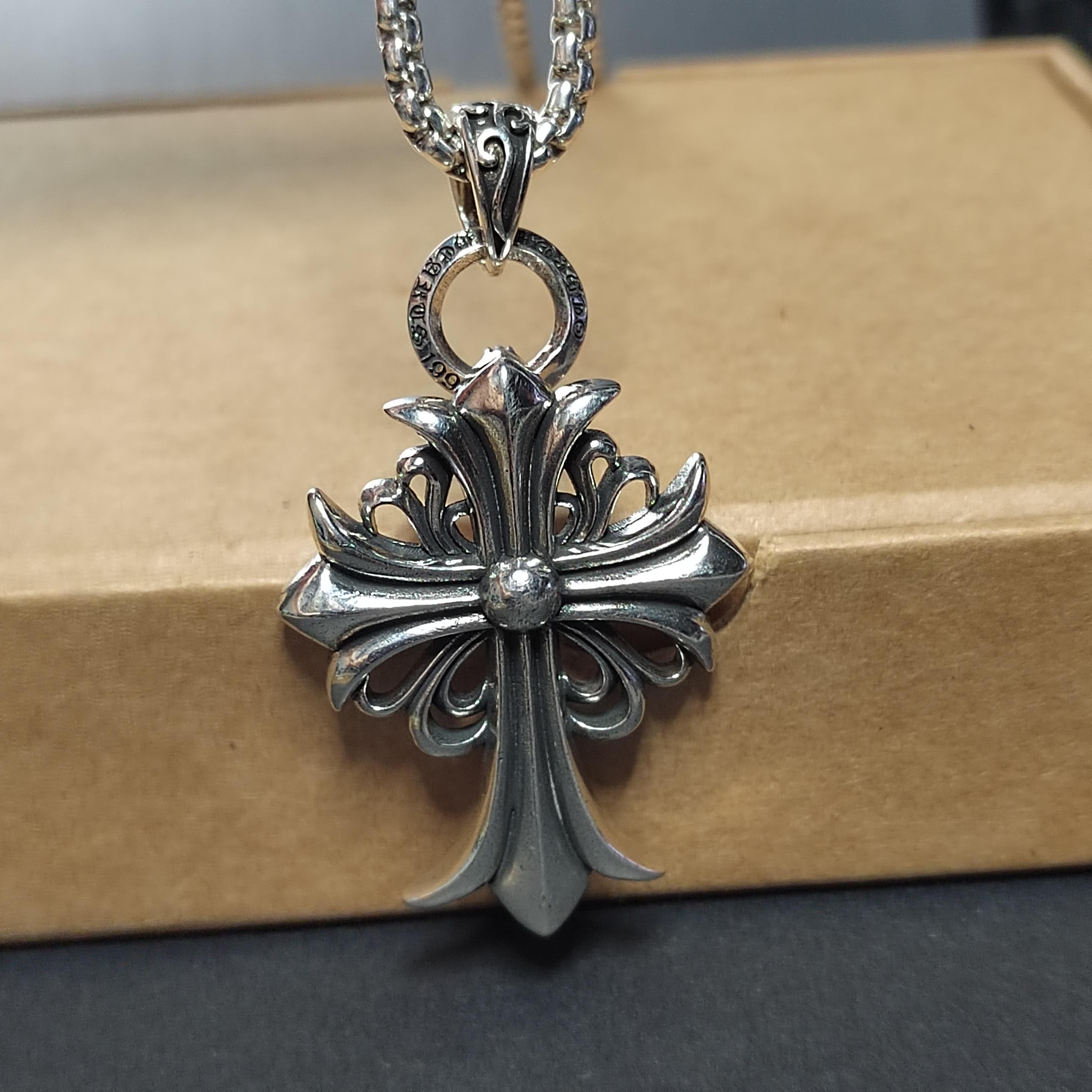 Silver cross pendant necklace on a cardboard box