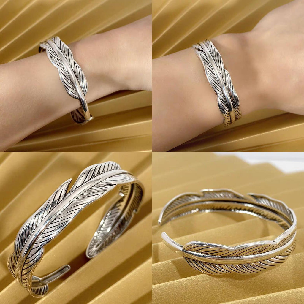 Silver feather-shaped bracelet on a wrist against a gold background