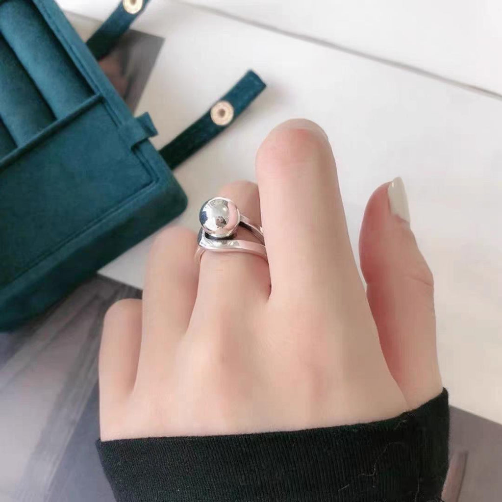 Silver ring on a finger with a teal jewelry box in the background