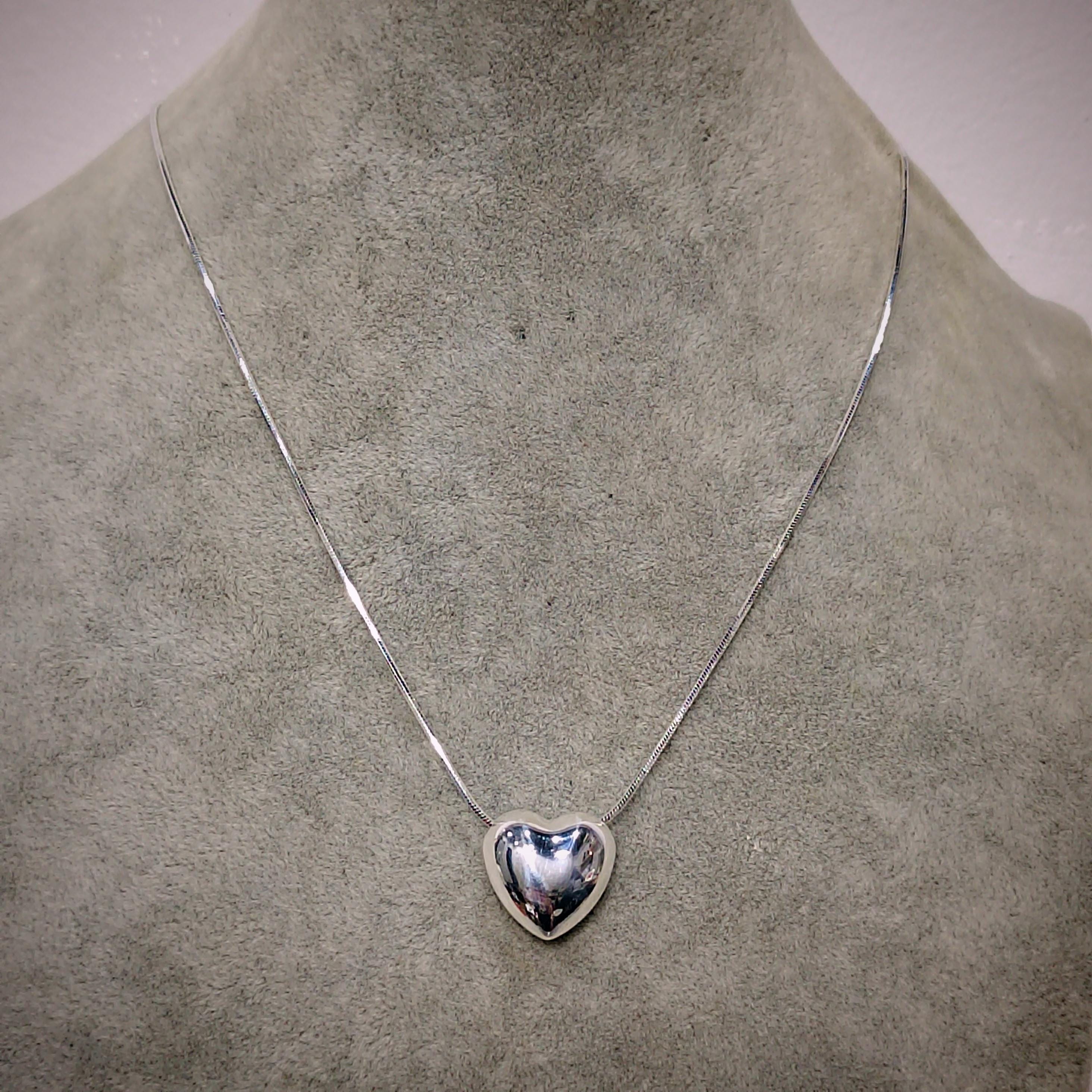 Silver heart-shaped pendant necklace on a mannequin neck.
