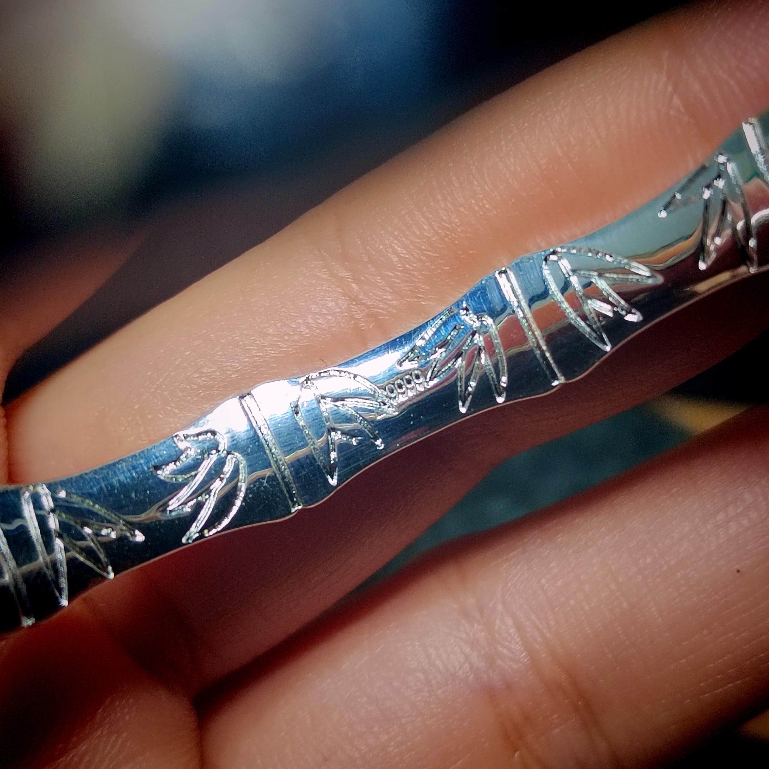 Silver bracelet with intricate designs on a person's wrist
