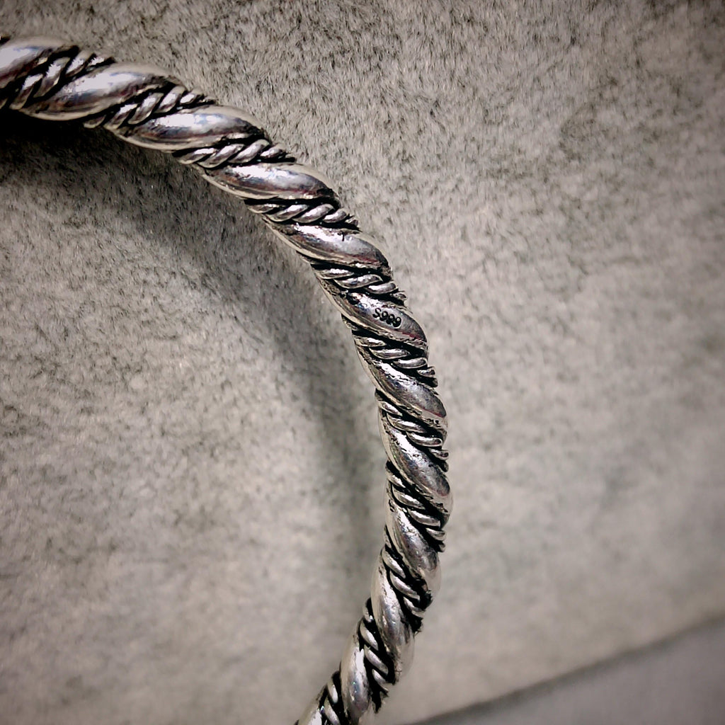 Silver braided bracelet on a textured gray background