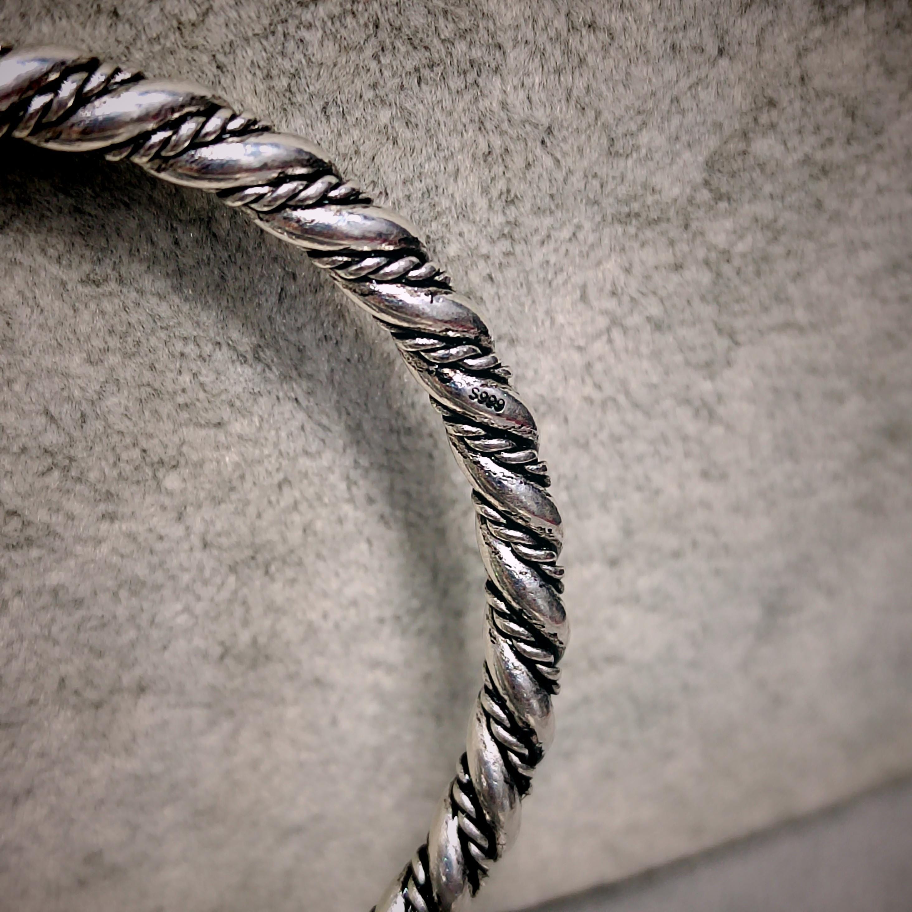 Silver braided bracelet on a textured gray background
