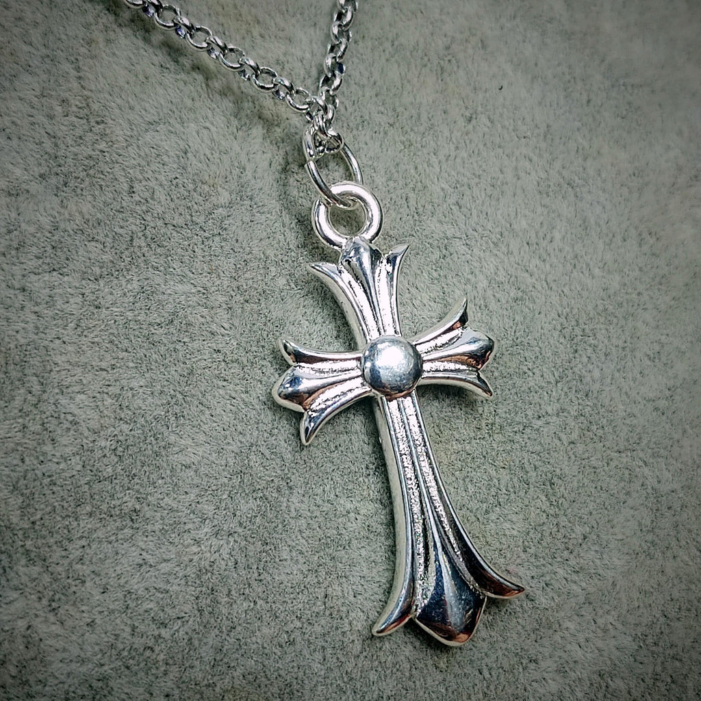 Silver cross pendant necklace on a textured gray background