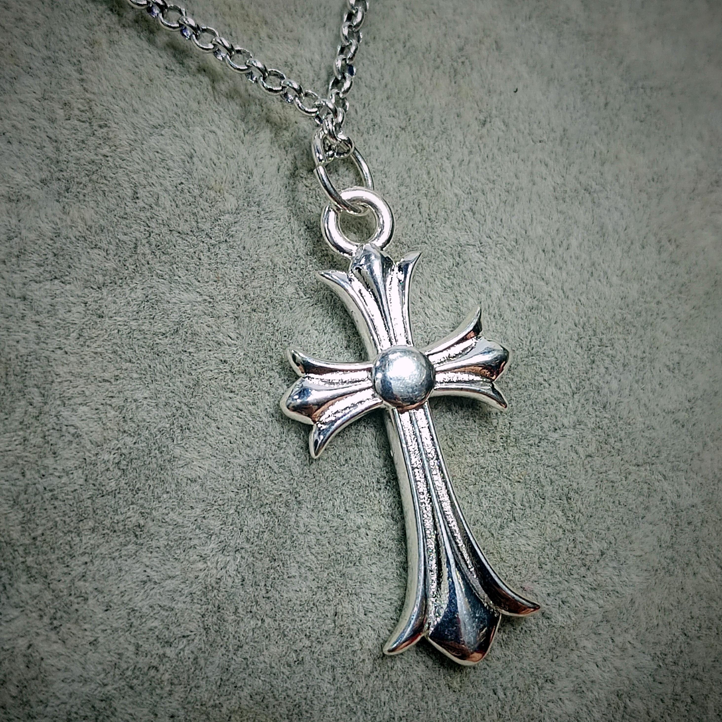 Silver cross pendant necklace on a textured gray background