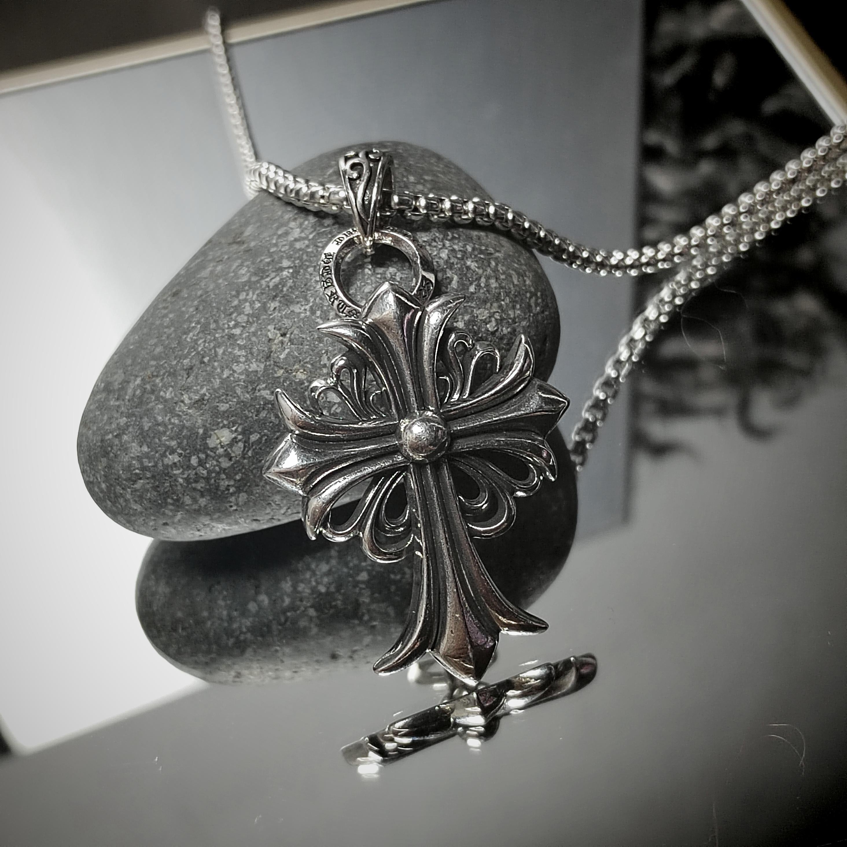 Silver cross pendant necklace on a stone surface