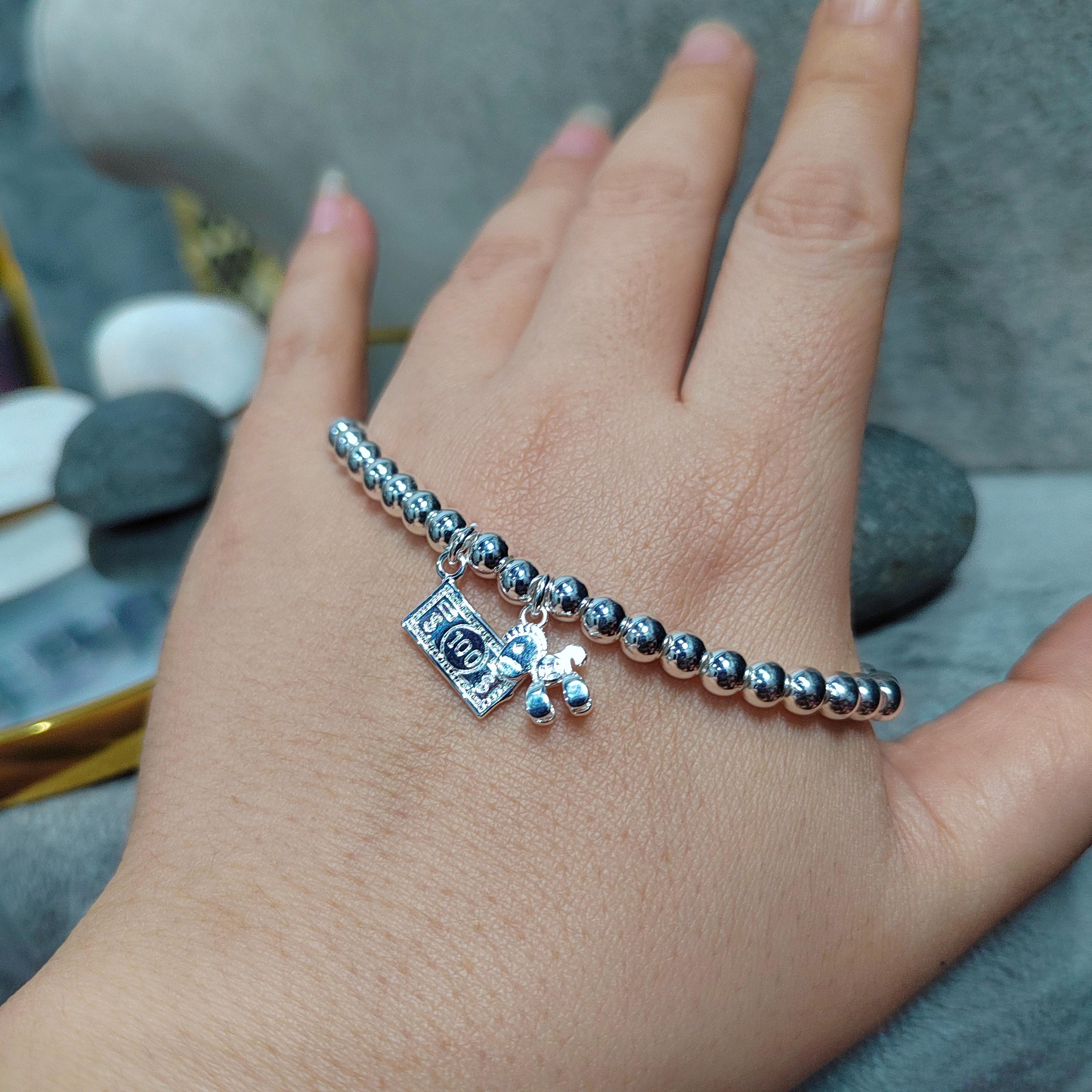 Hand wearing a beaded bracelet with charms on a blurred natural background