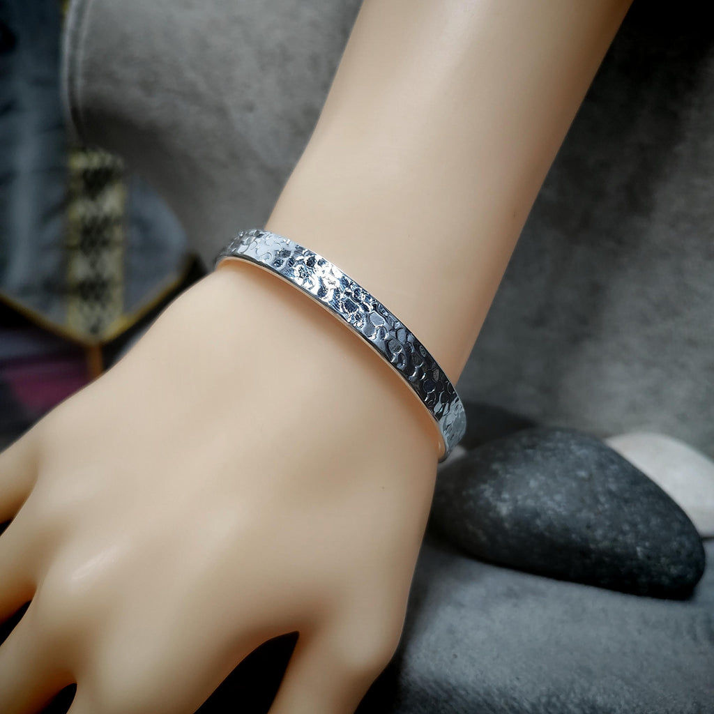 Silver bracelet on a mannequin hand with a blurred background