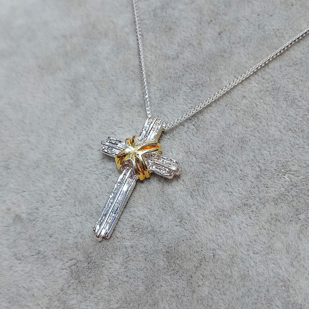 Cross-shaped pendant necklace on a gray surface