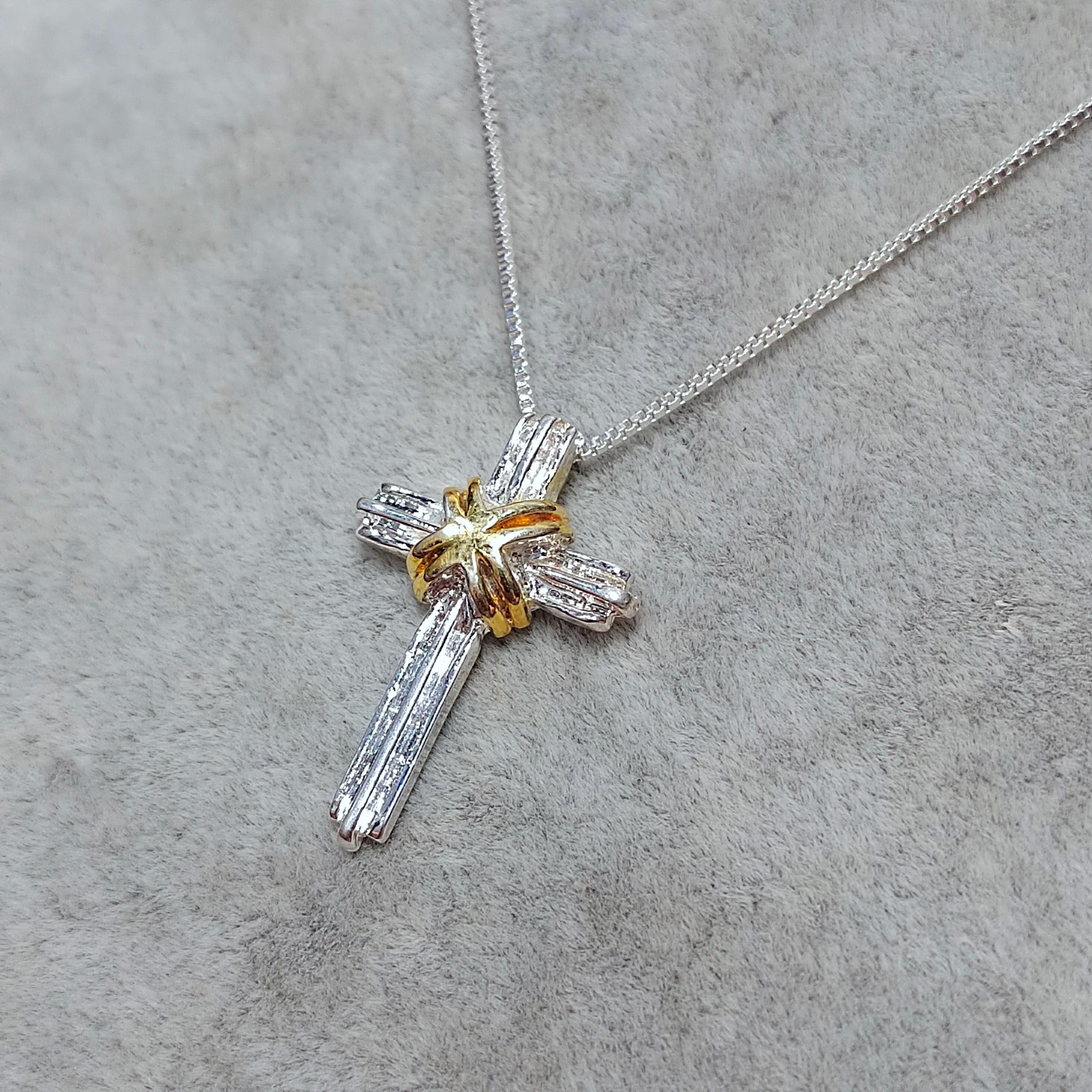 Cross-shaped pendant necklace on a gray surface