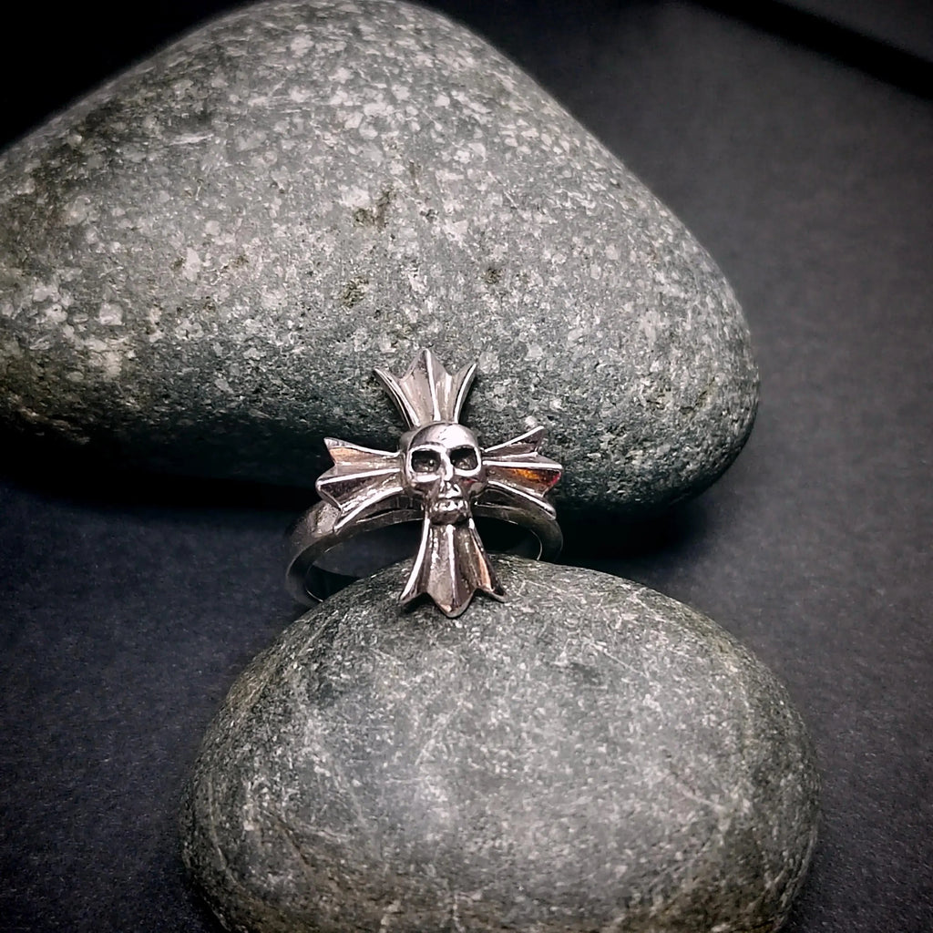 Silver ring with skull design on a stone surface