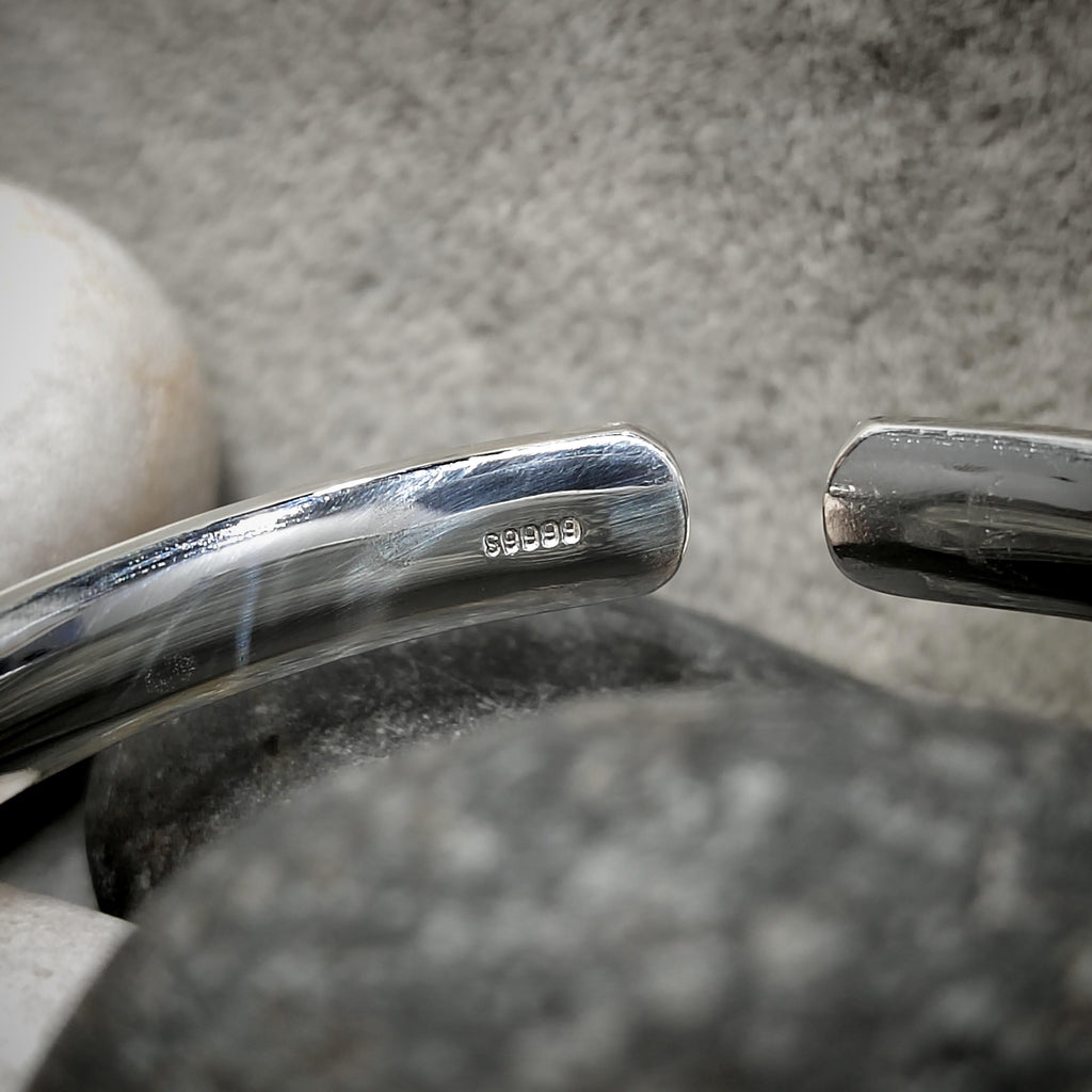 Close-up of a silver spoon with '925' stamp on a stone surface