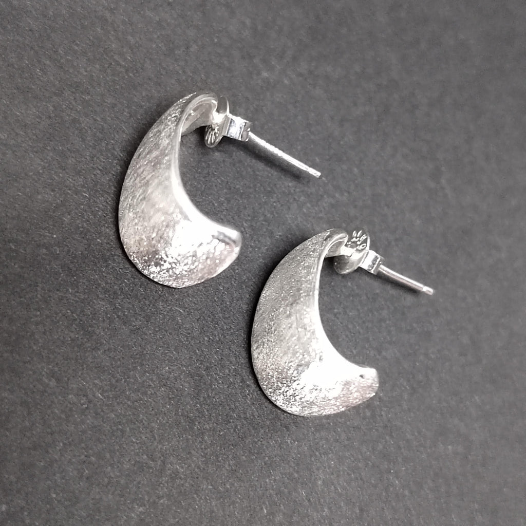 Silver crescent moon earrings on a gray background