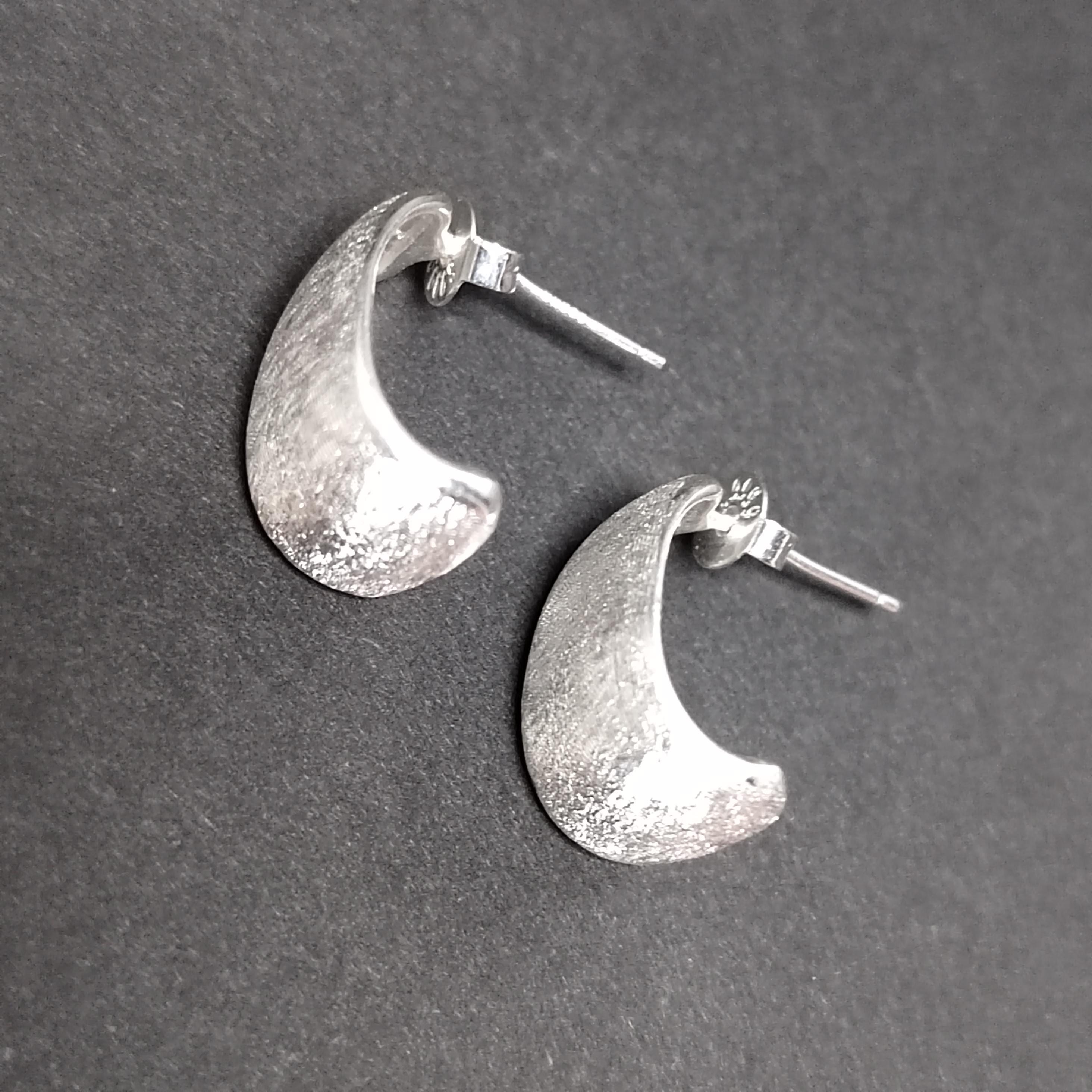 Silver crescent moon earrings on a gray background
