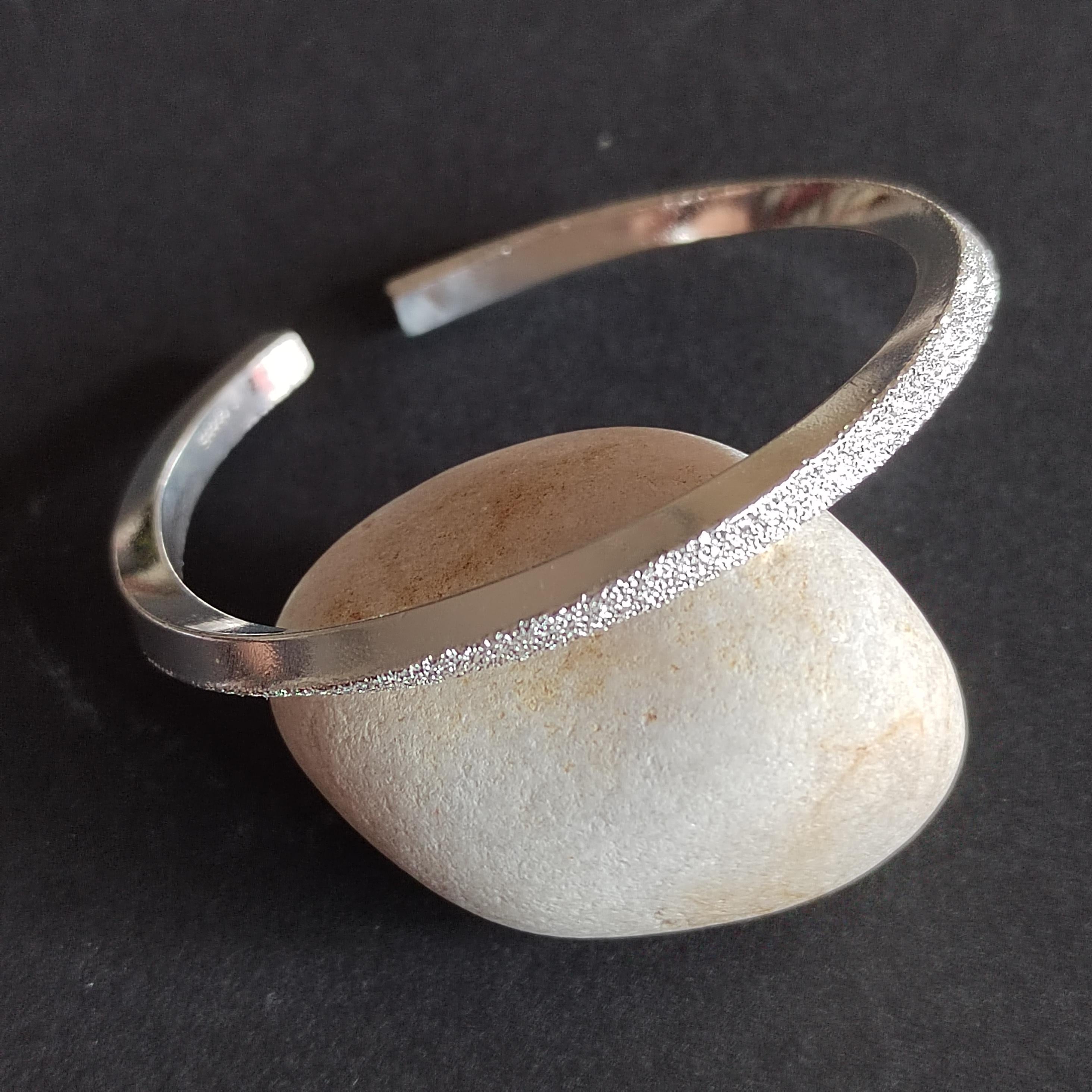 Silver bracelet on a stone against a dark background