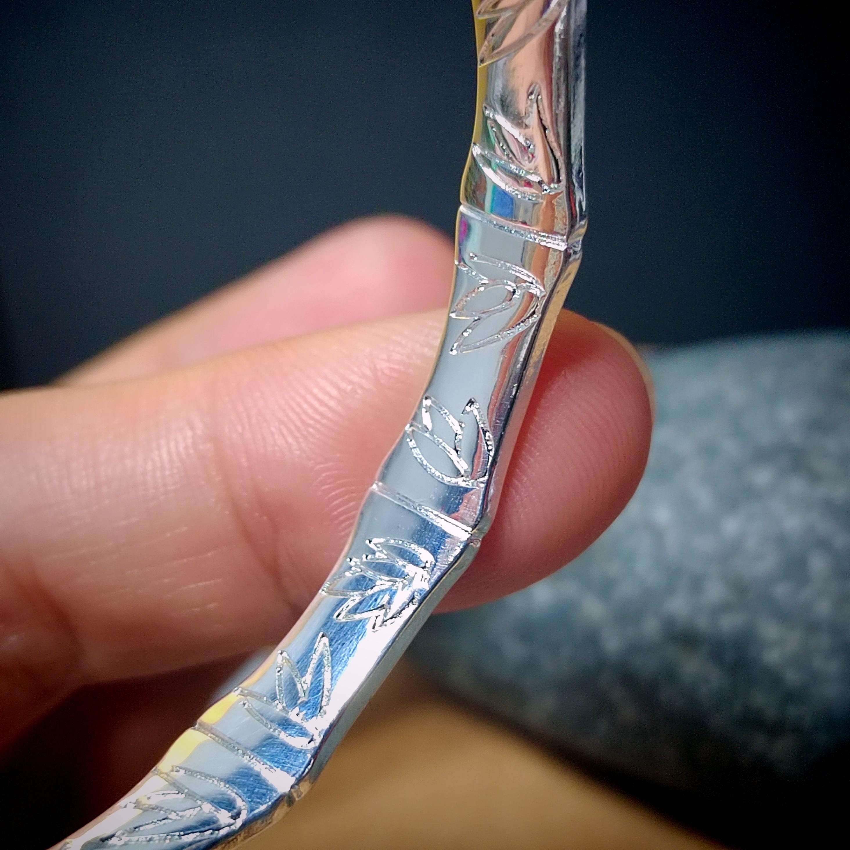 Silver-handled knife with floral patterns held by a hand against a dark background
