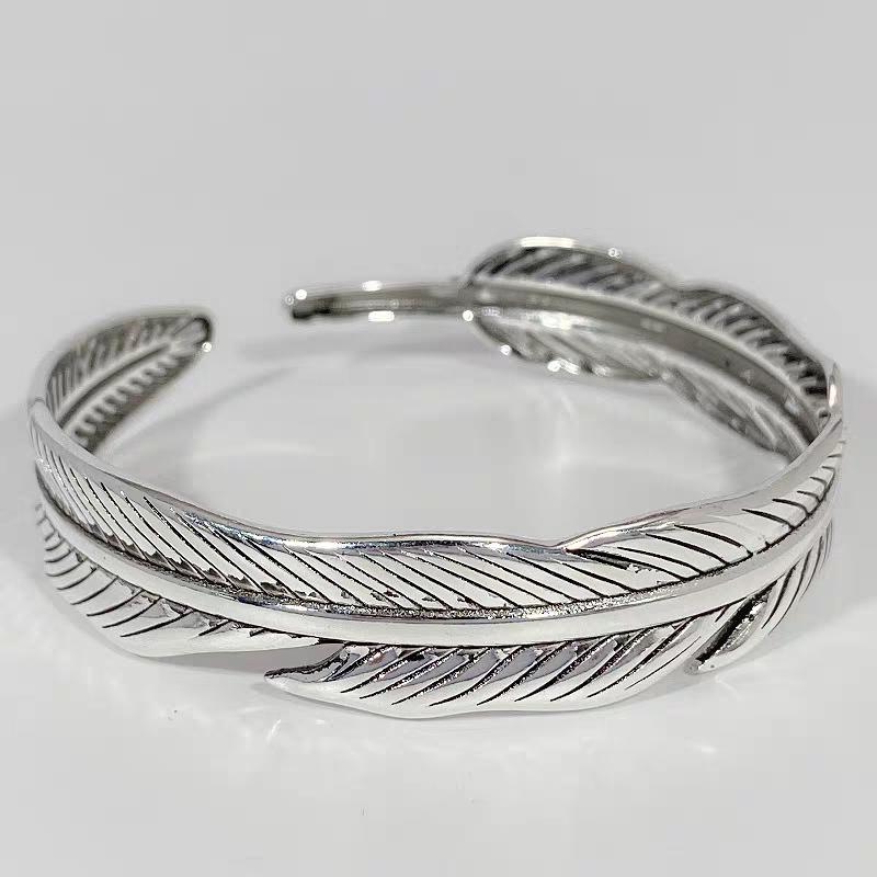 Silver feather-patterned bracelet on a light gray background