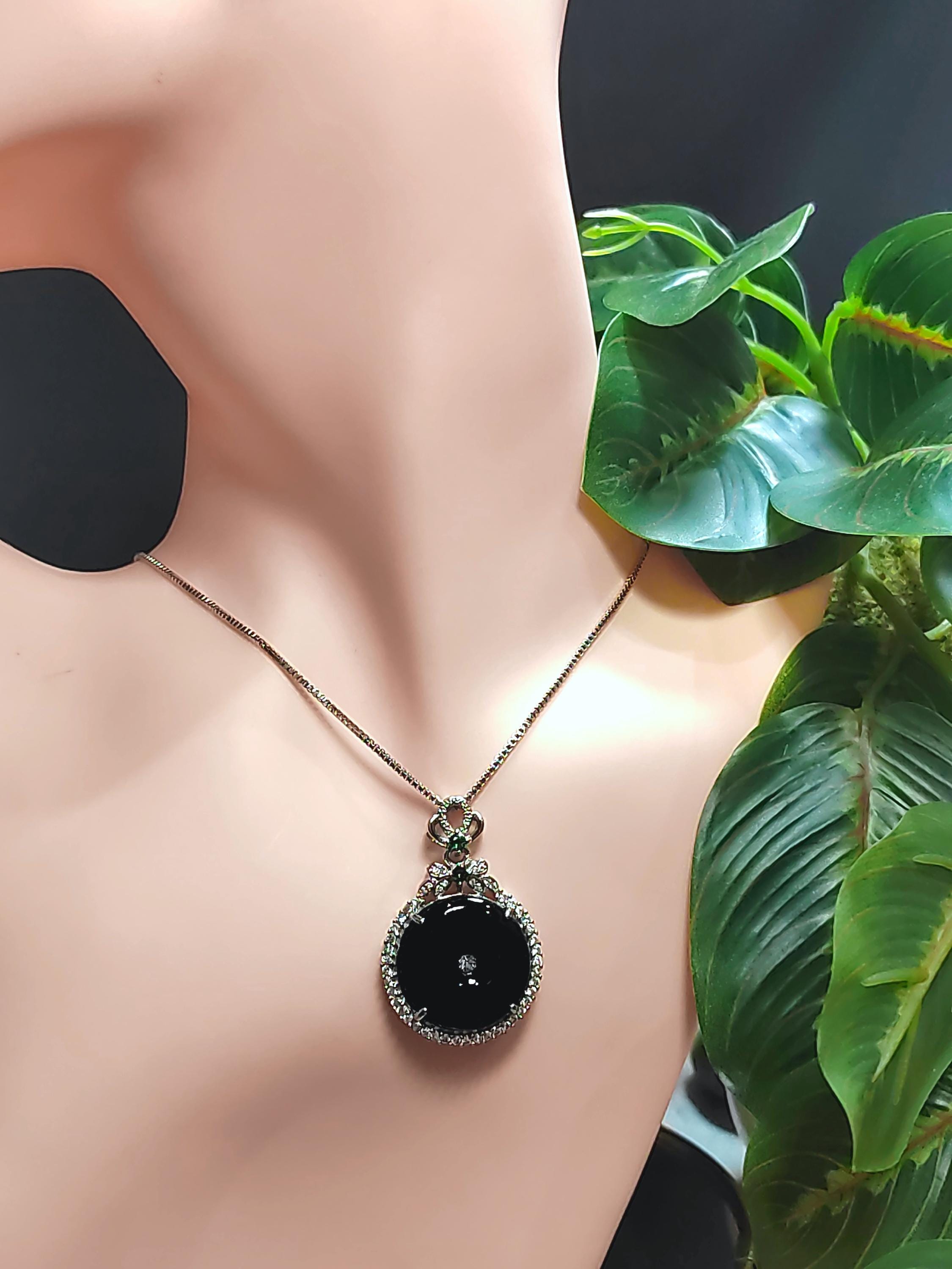 Black pendant necklace on a mannequin with green leaves in the background
