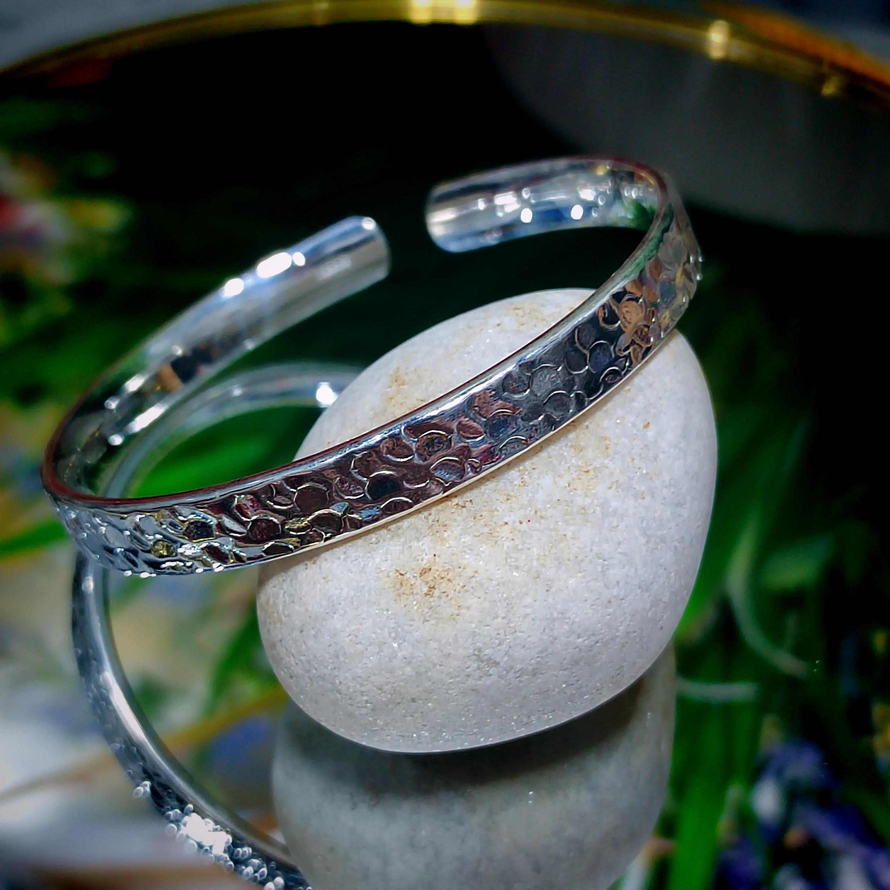 Silver bracelet on a white stone with a blurred natural background