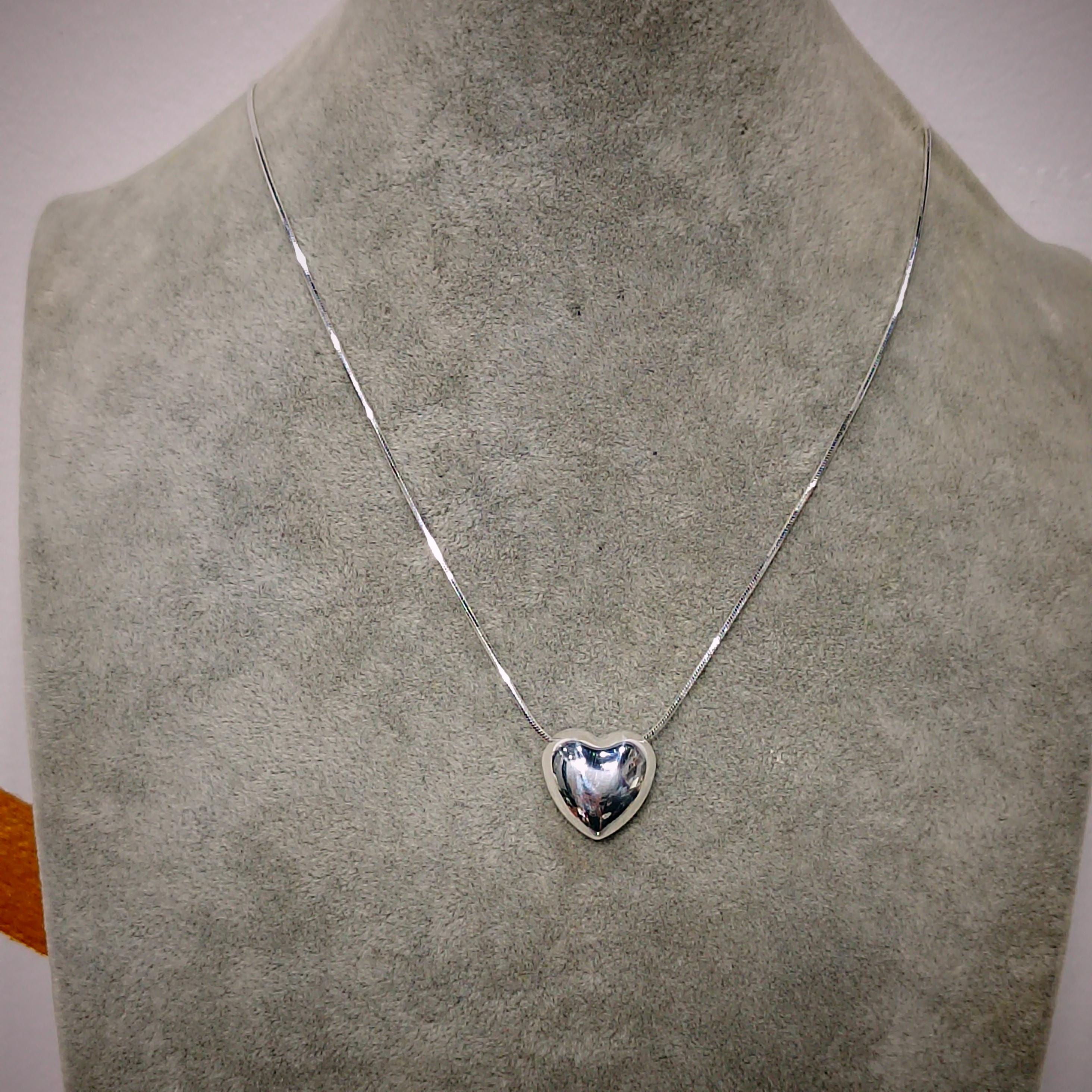 Silver heart-shaped pendant necklace on a mannequin bust.