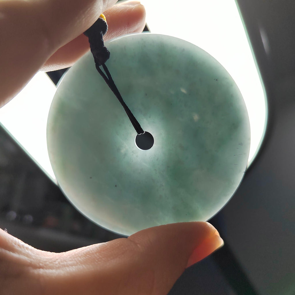 Person holding a jade pendant with a blurred background
