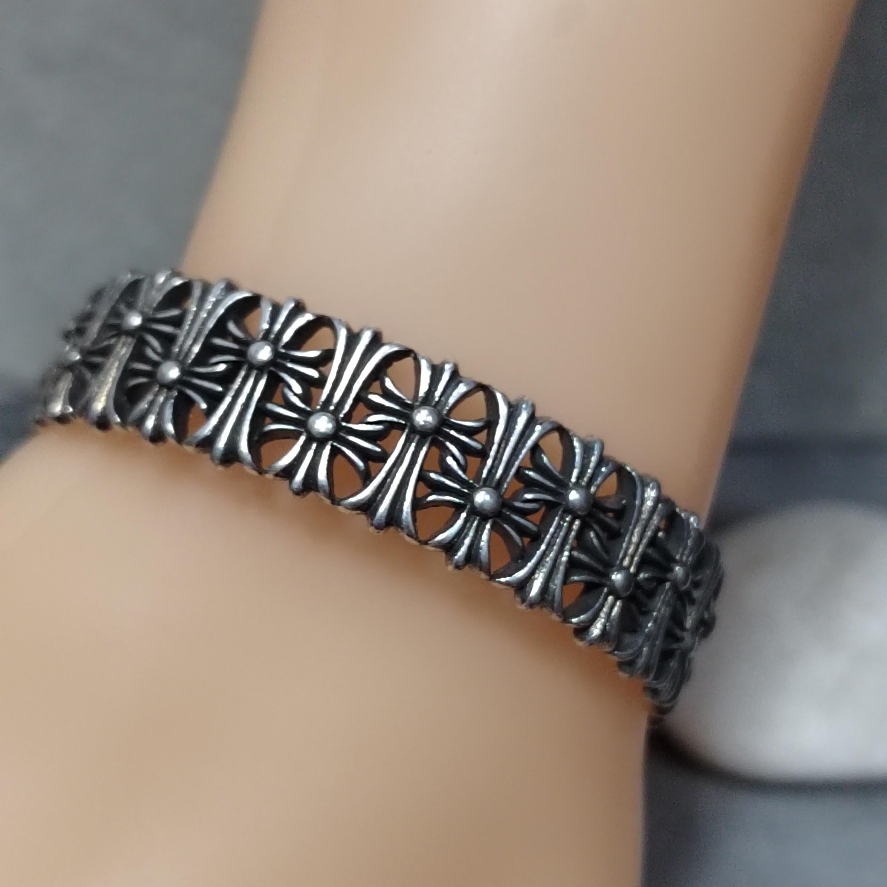 Silver bracelet with intricate design on a wrist against a neutral background