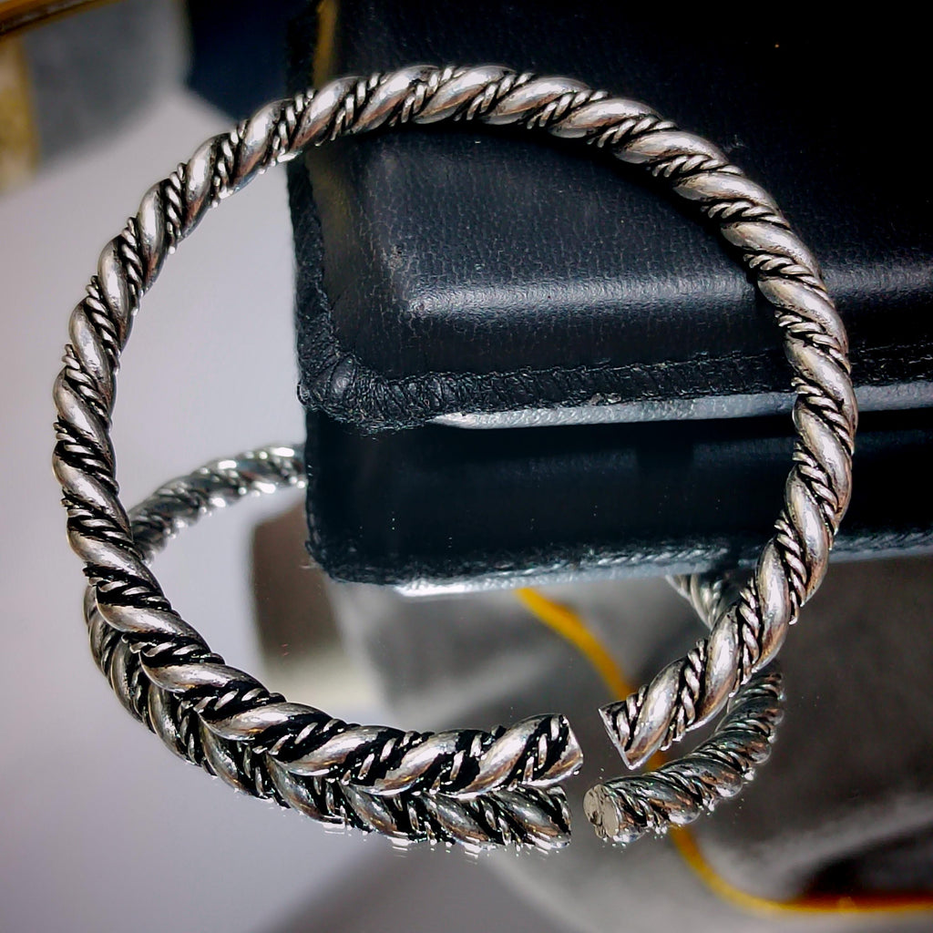 Silver braided bracelet on a black leather surface
