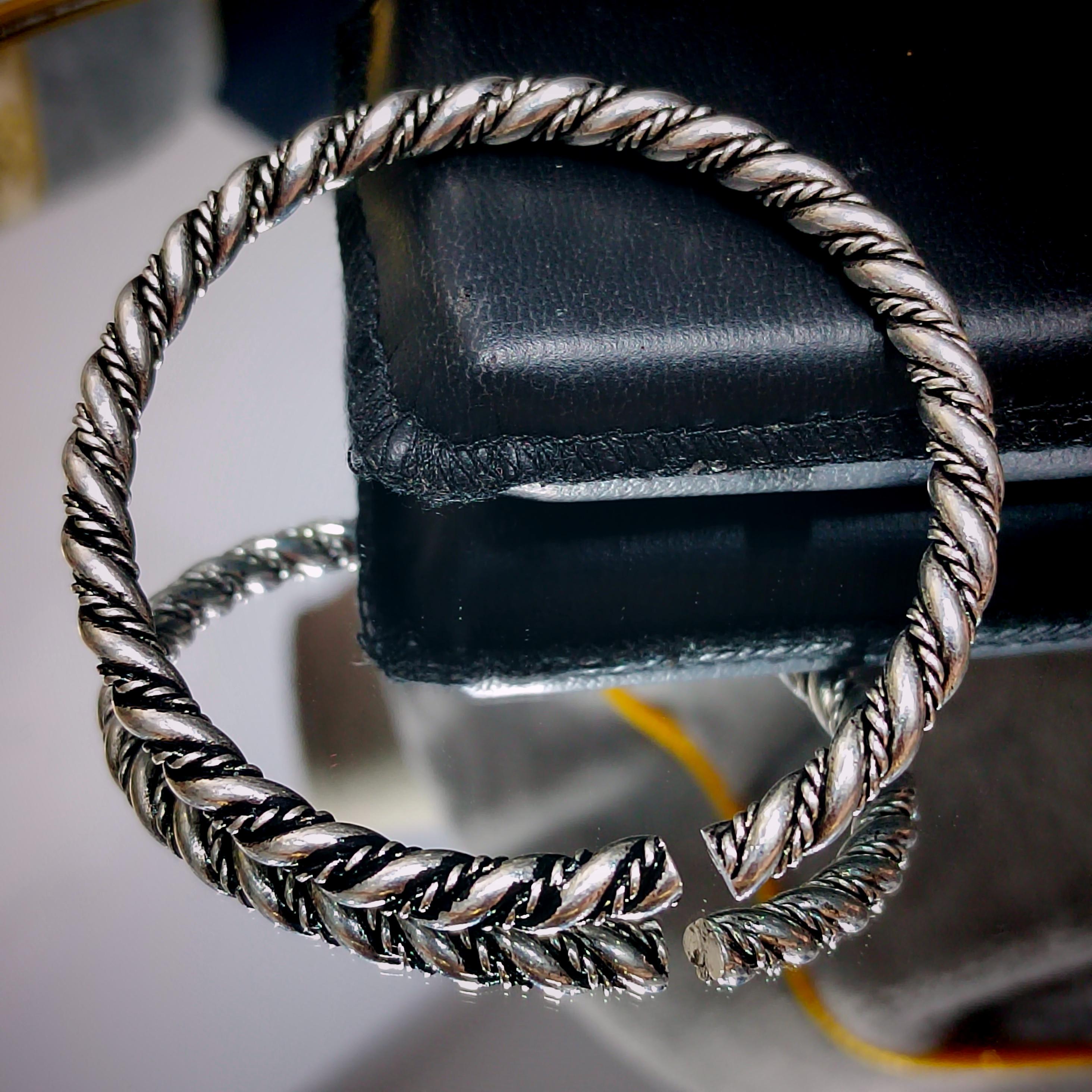 Silver braided bracelet on a black leather surface