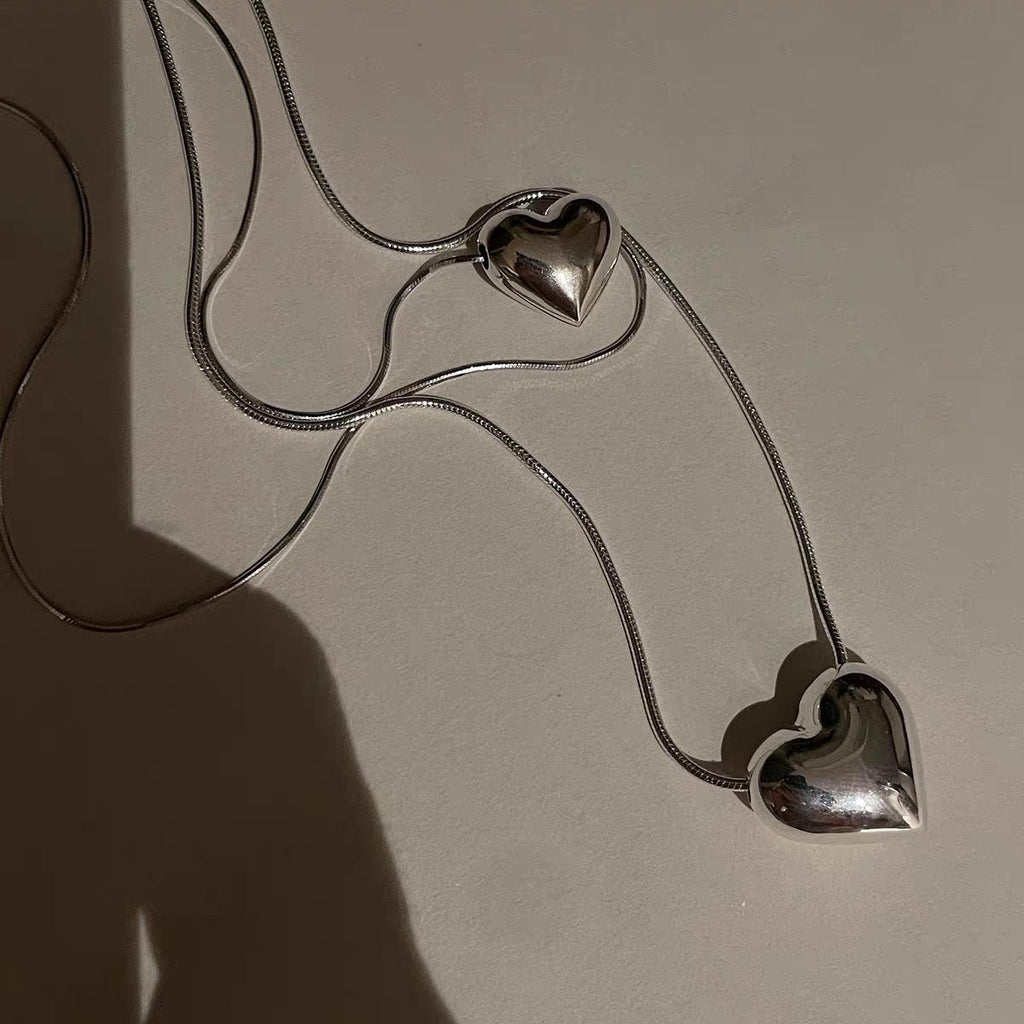 Silver heart-shaped necklace on a beige background
