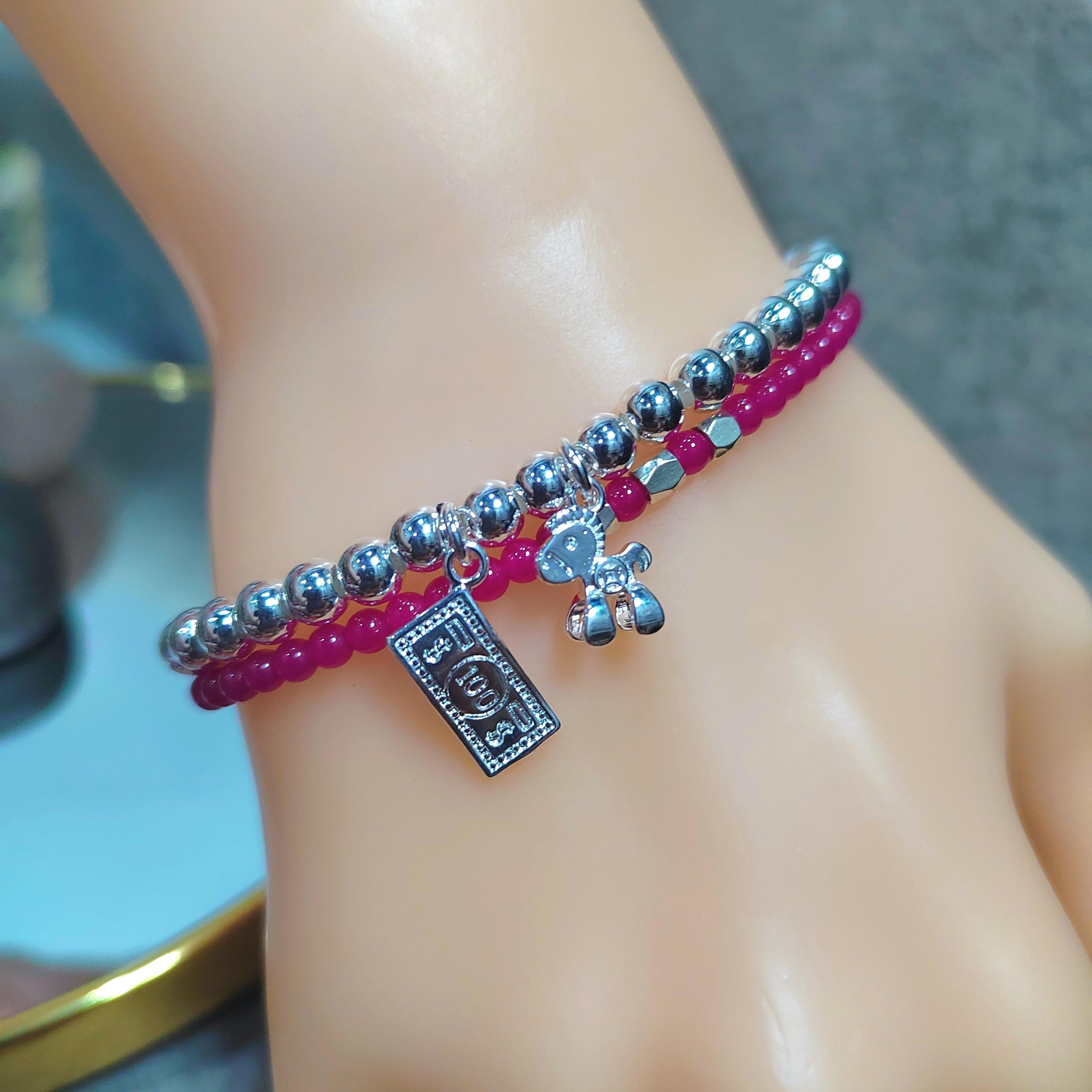 Bracelet with silver beads and a tag on a wrist against a blurred background
